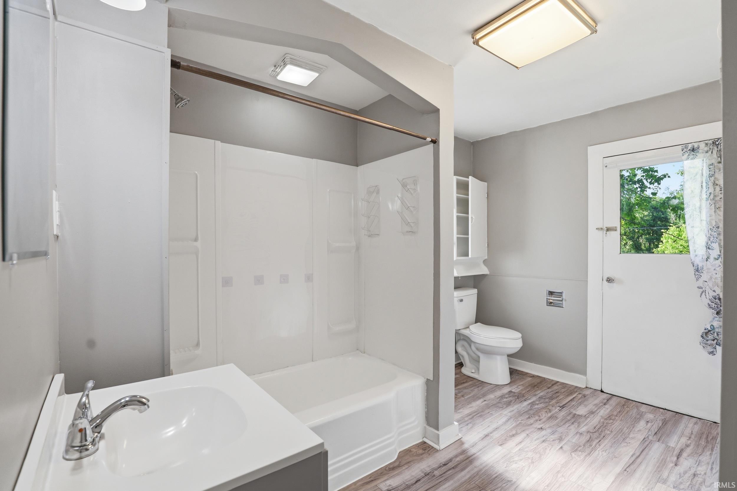 Full bathroom featuring a tub/shower combination, a vanity with an integrated sink, and wood-finish flooring