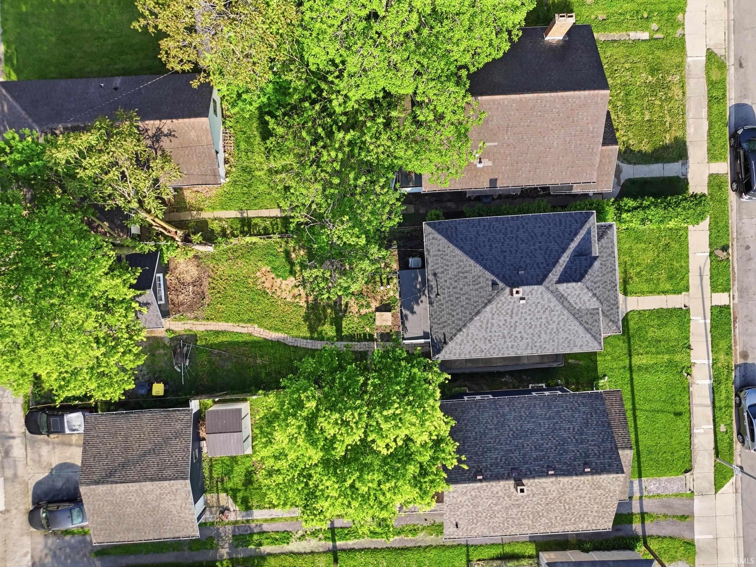 Aerial perspective showcasing a residential property with a multi-gabled roofline and an accompanying structure featuring a similar roof