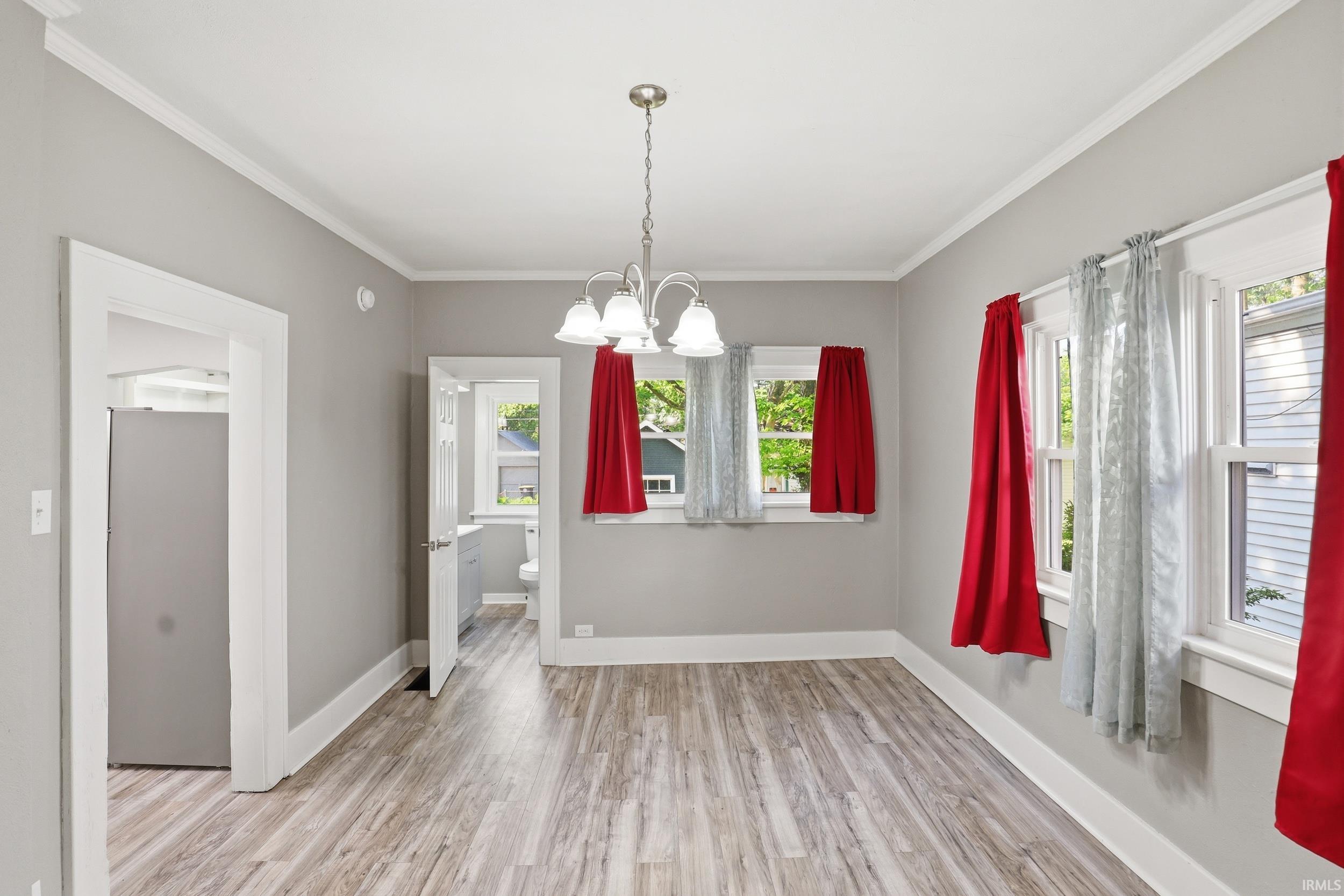 Spacious room featuring wood-finish flooring, light grey wall paint, and white trim