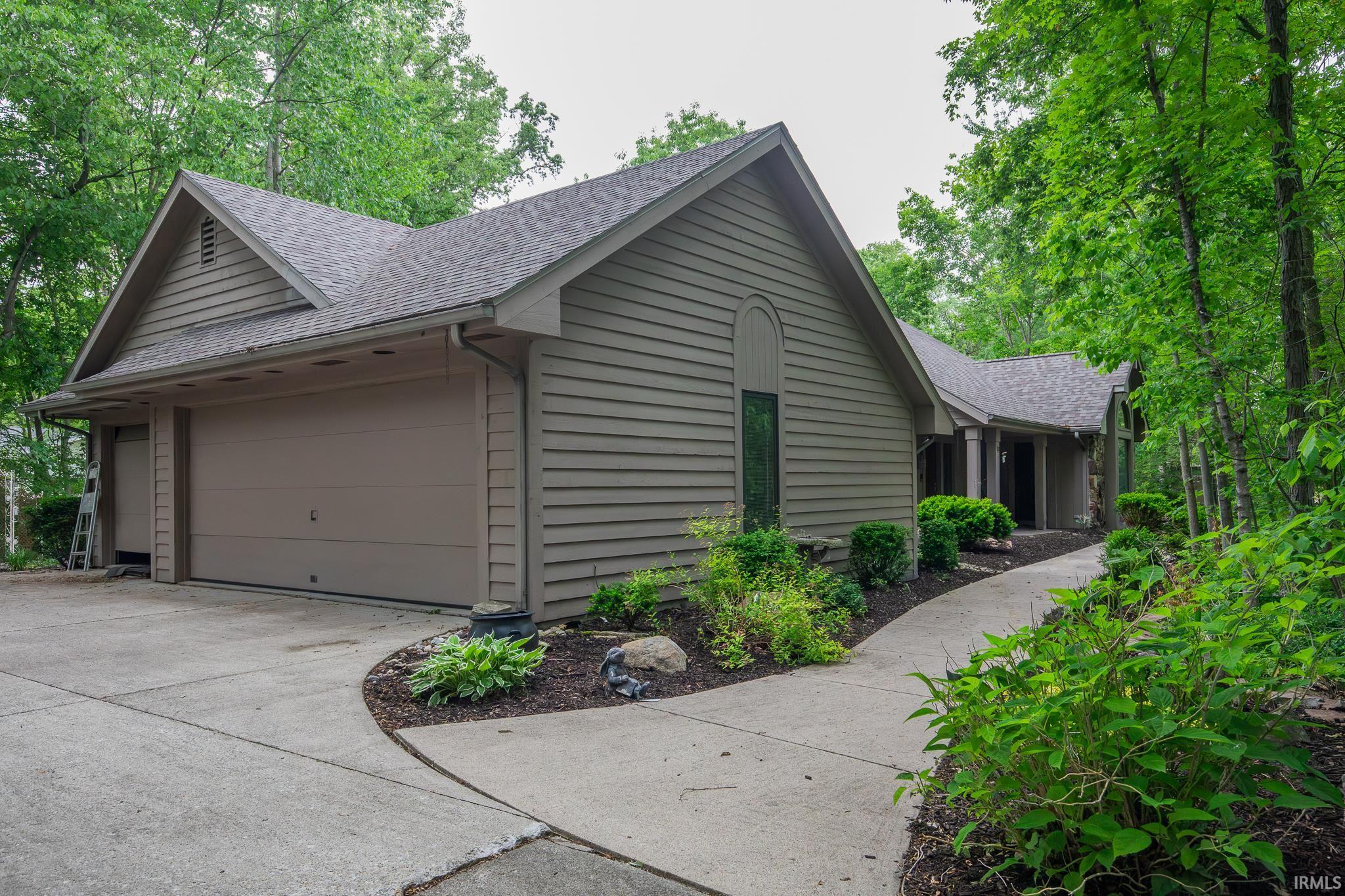 Siding exterior with attached garage, concrete driveway, and curved walkway