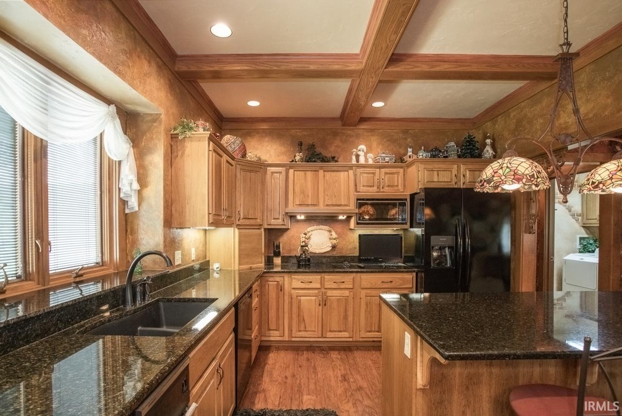 Kitchen featuring wood cabinetry, dark granite countertops, and wood-finish flooring