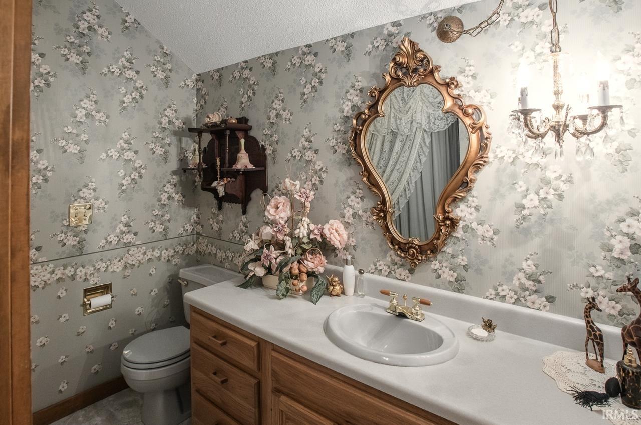 Bathroom featuring a single-basin vanity with wood cabinetry, a light-toned countertop, and gold-toned hardware