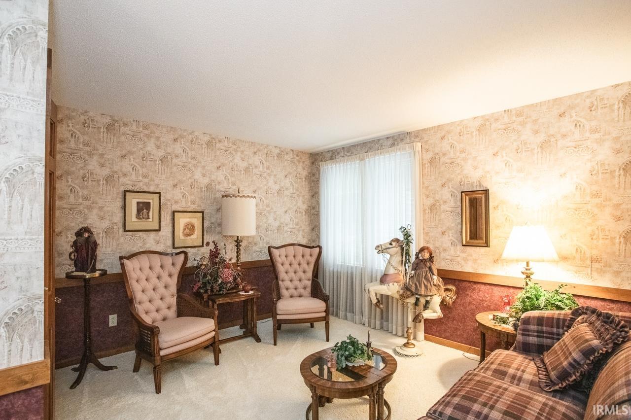 Bright interior space featuring patterned wallpaper, neutral carpeting, and a window with sheer coverings