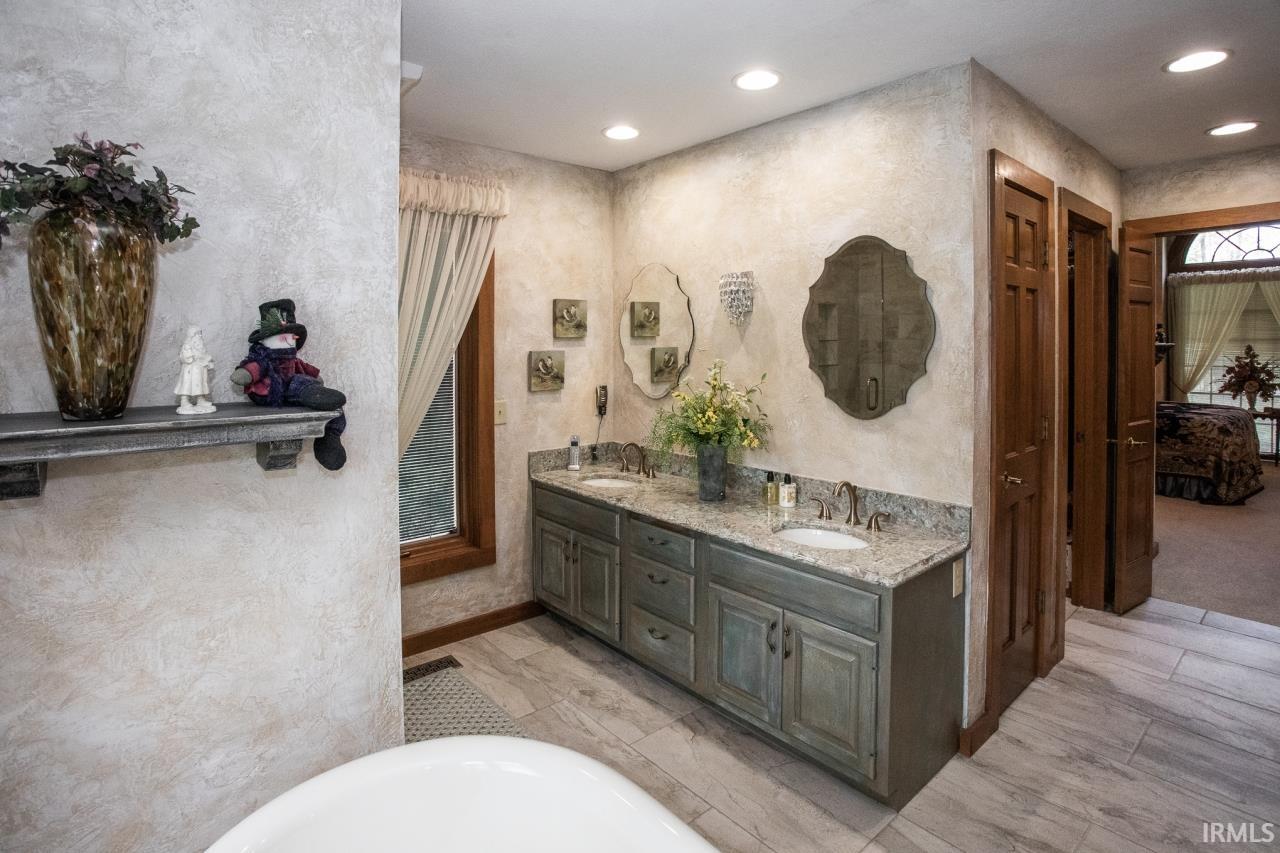 Double vanity with distressed gray cabinetry, light granite-style countertop, and dual undermount sinks