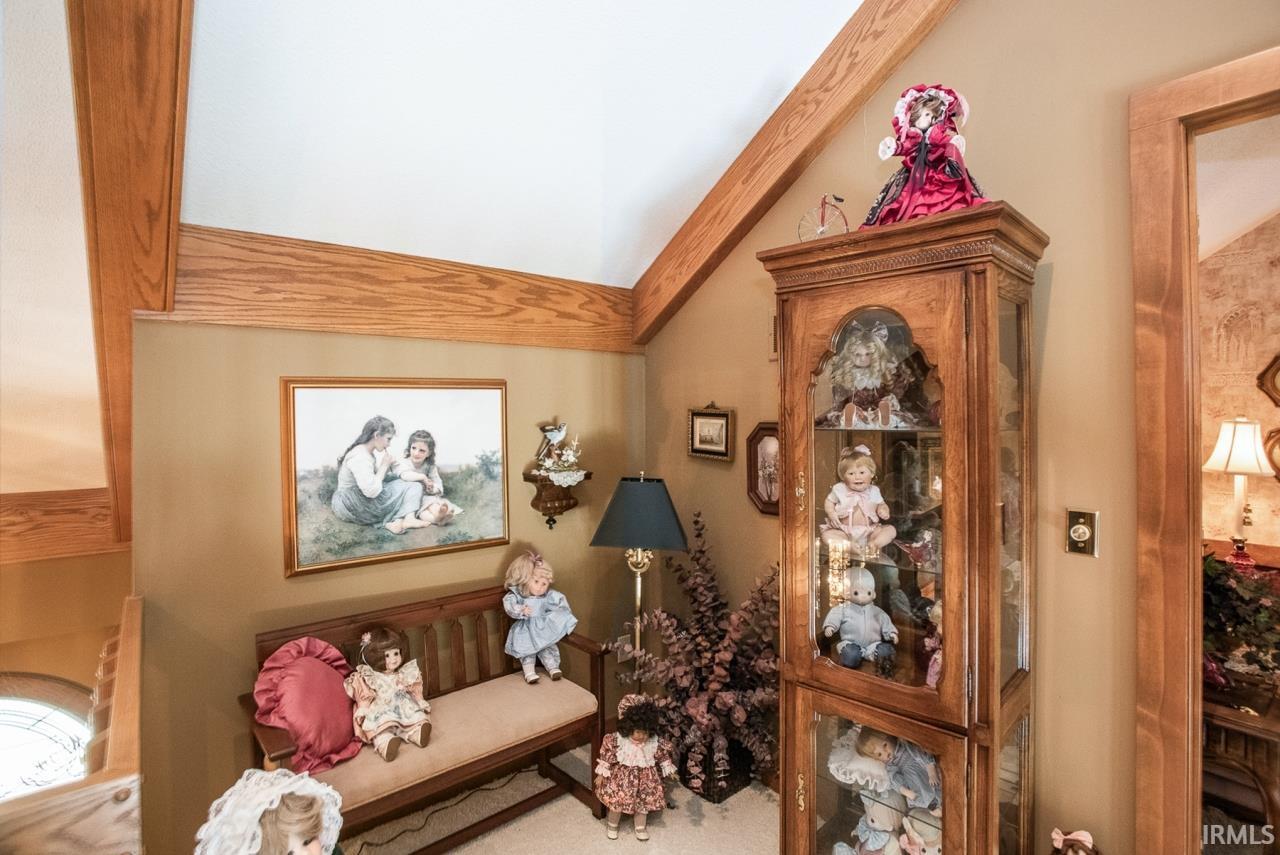 Vaulted ceiling with exposed wood beams, wall-mounted art, and a wood-finish display cabinet