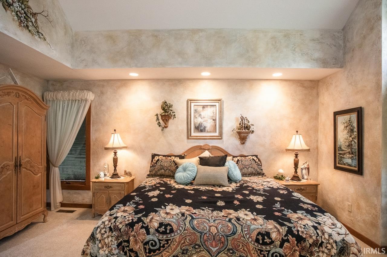 Bedroom featuring a recessed ceiling, textured wall finish, and wood-finish window trim