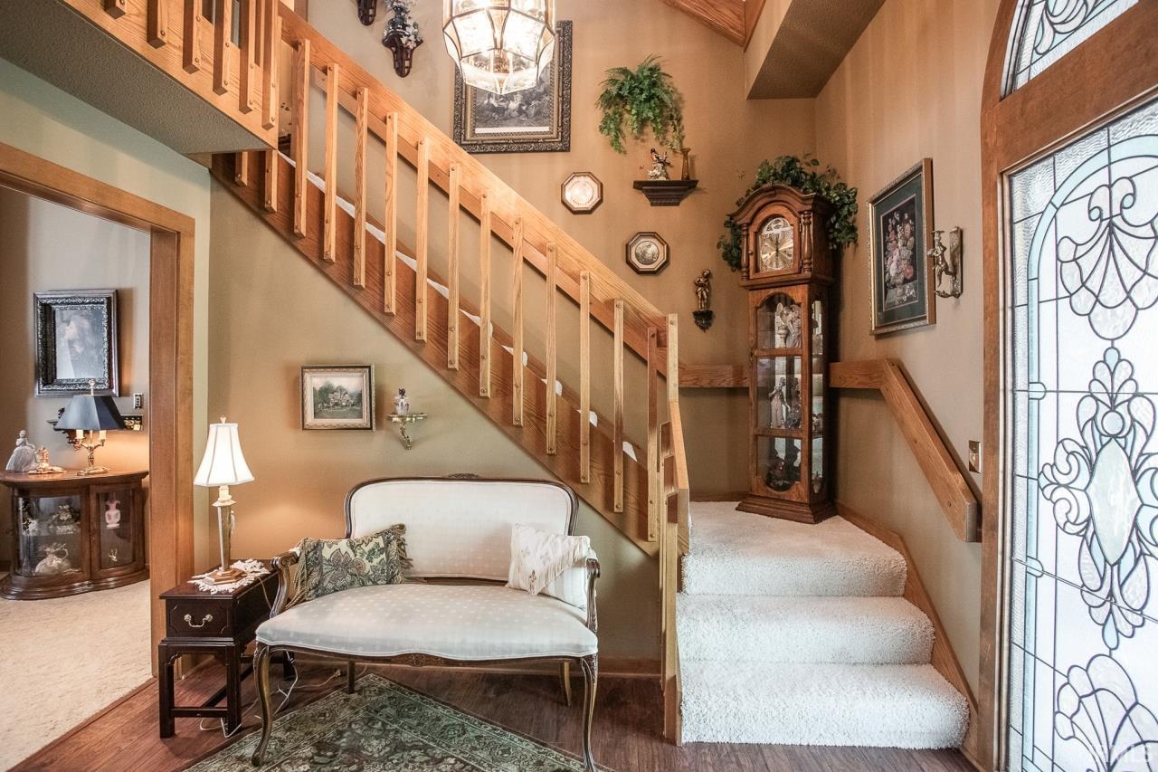 Foyer featuring a grand staircase with wood railings, carpeted treads, and wood-finish flooring