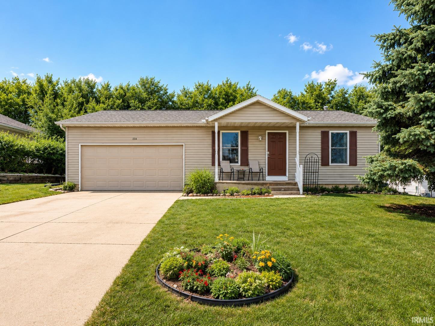 Ranch-style exterior with beige siding, a covered front porch, and a two-car attached garage