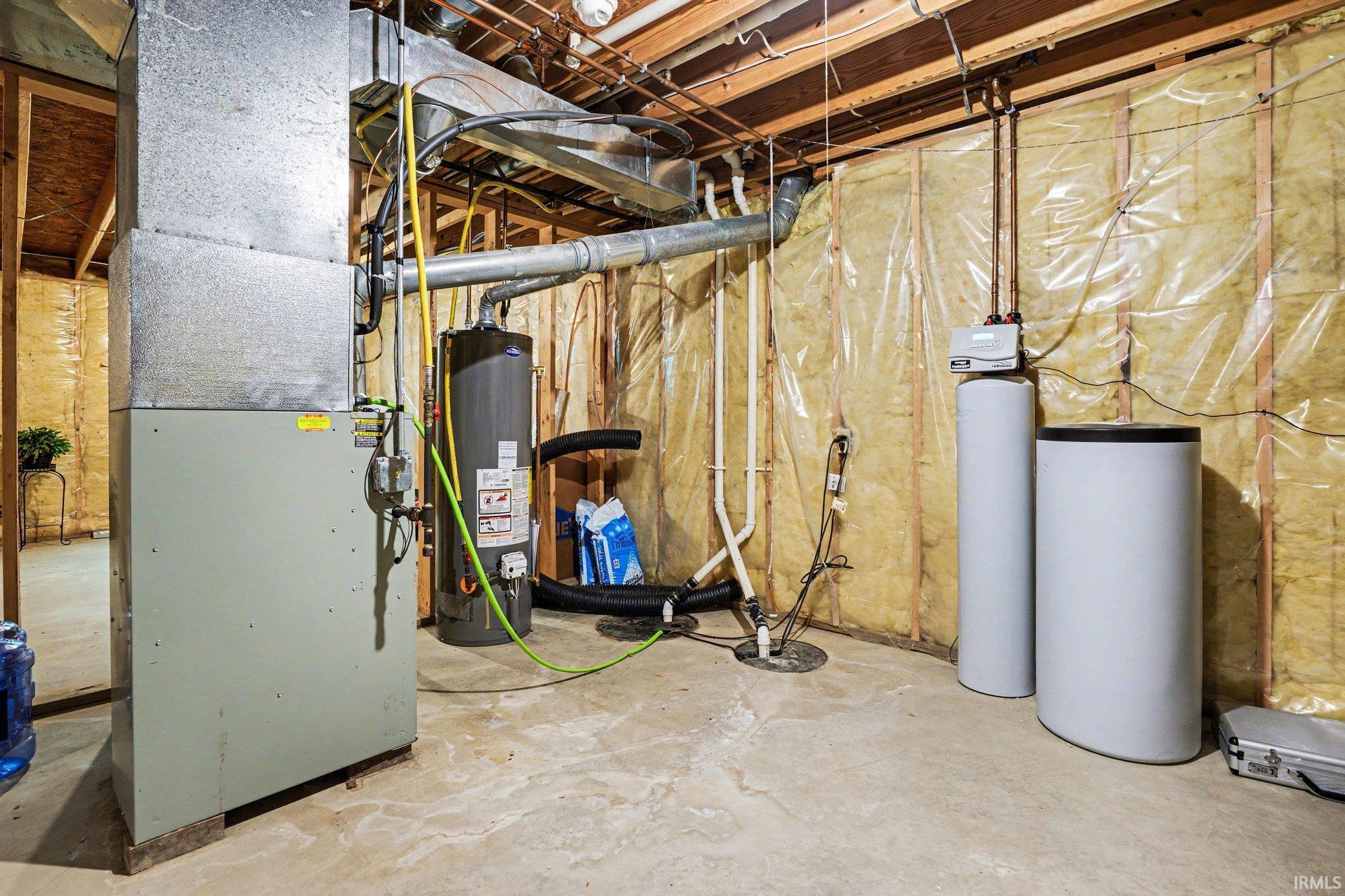 Utility area featuring a forced air furnace, water heater, water softener system, sump pump, and exposed wood joists