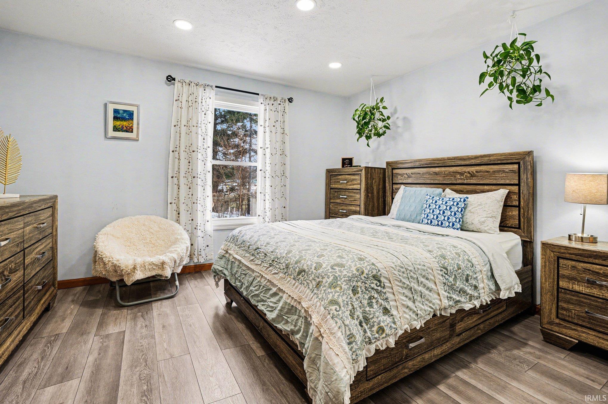 Bedroom featuring wood-finish flooring, recessed lighting, and a window with white trim