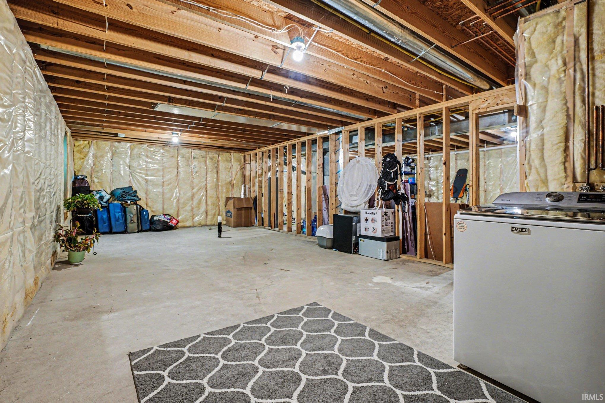Unfinished basement featuring exposed wood ceiling joists and concrete flooring