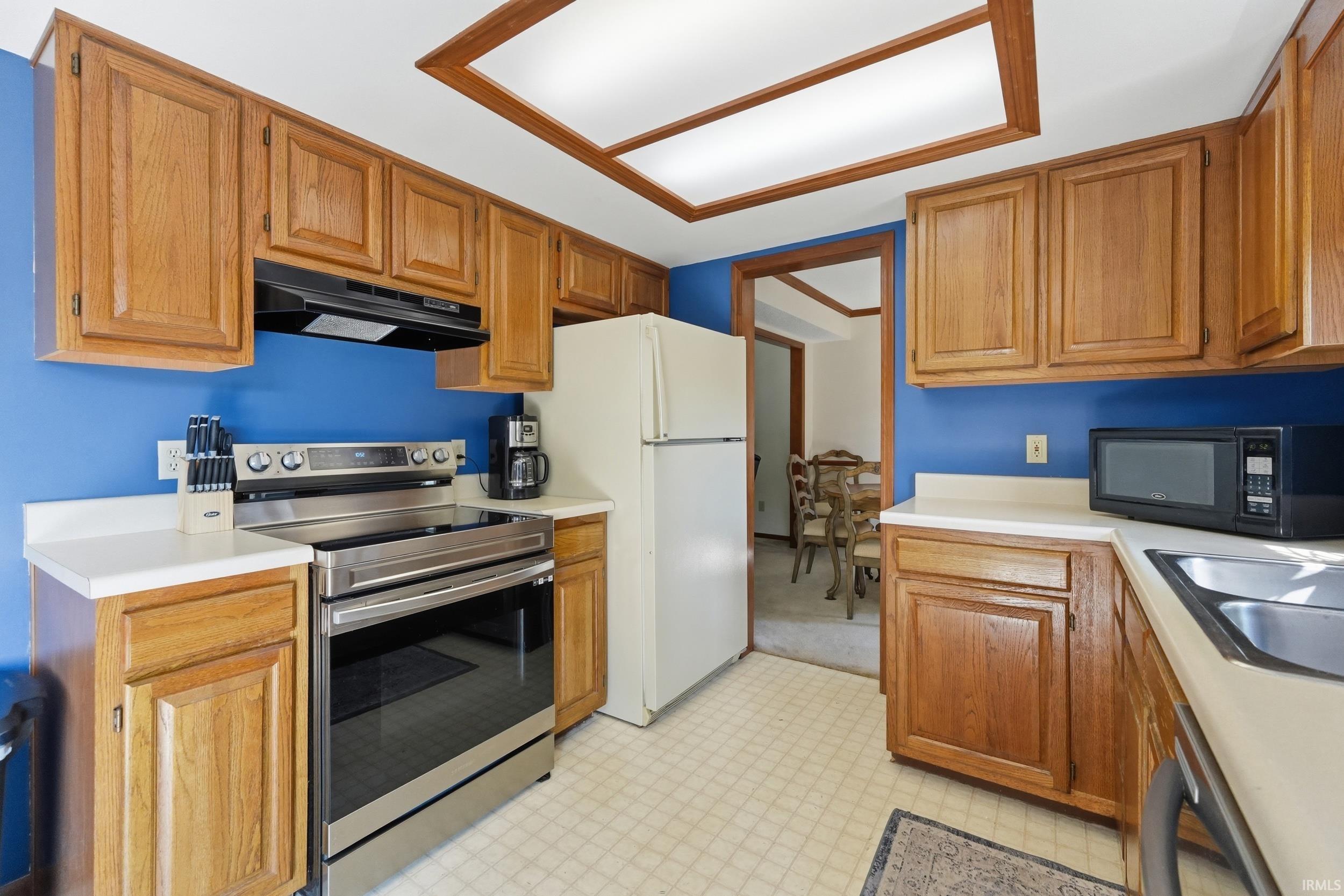 Kitchen featuring wood cabinetry, white countertops, built-in stainless steel range, and a double basin sink