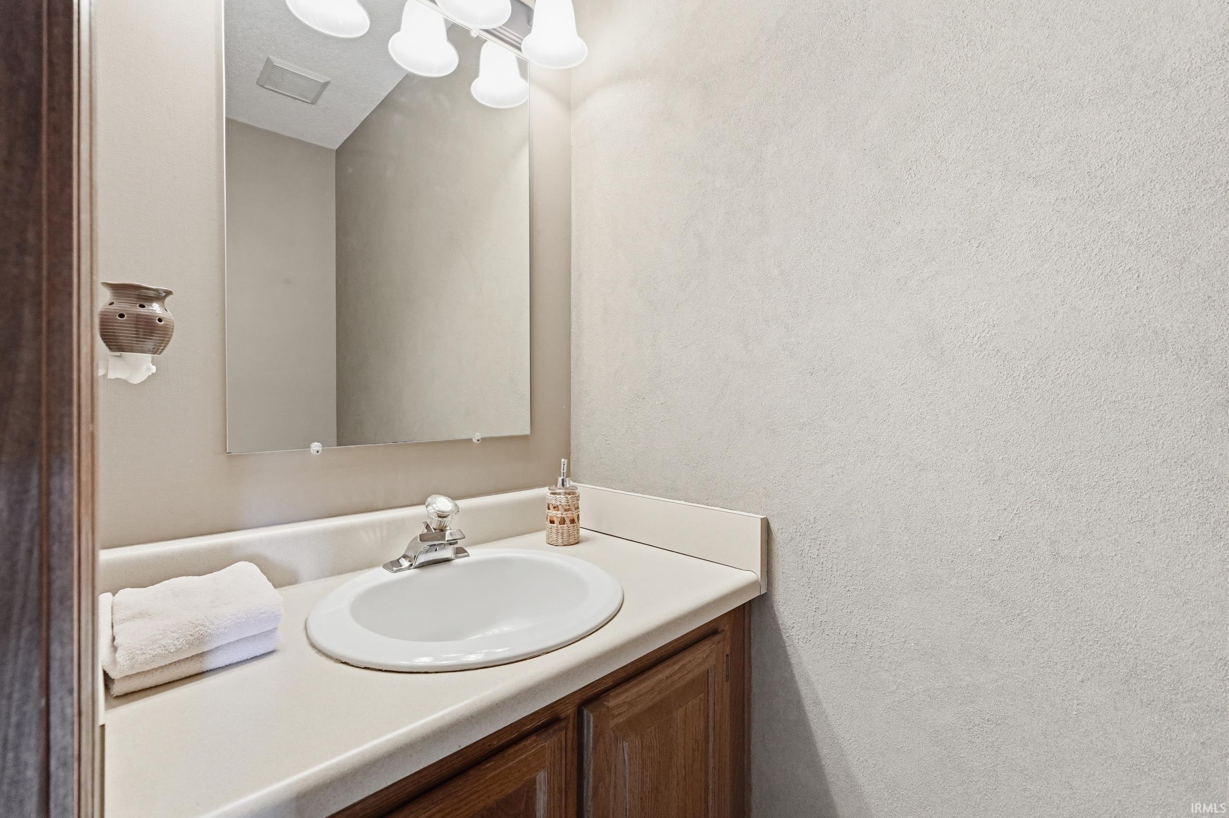 Bathroom vanity with an integrated white sink, chrome faucet, and wood-finish cabinetry