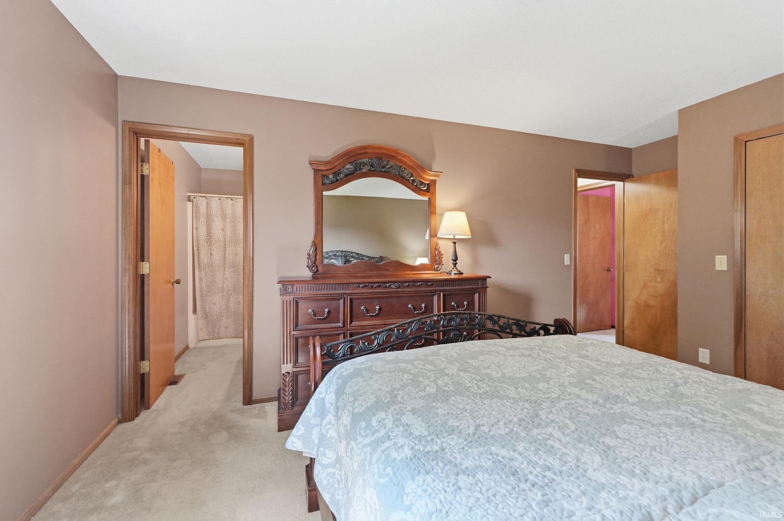 Carpeted bedroom featuring neutral wall tones, wood-trimmed doorways, and a built-in closet with a solid wood door