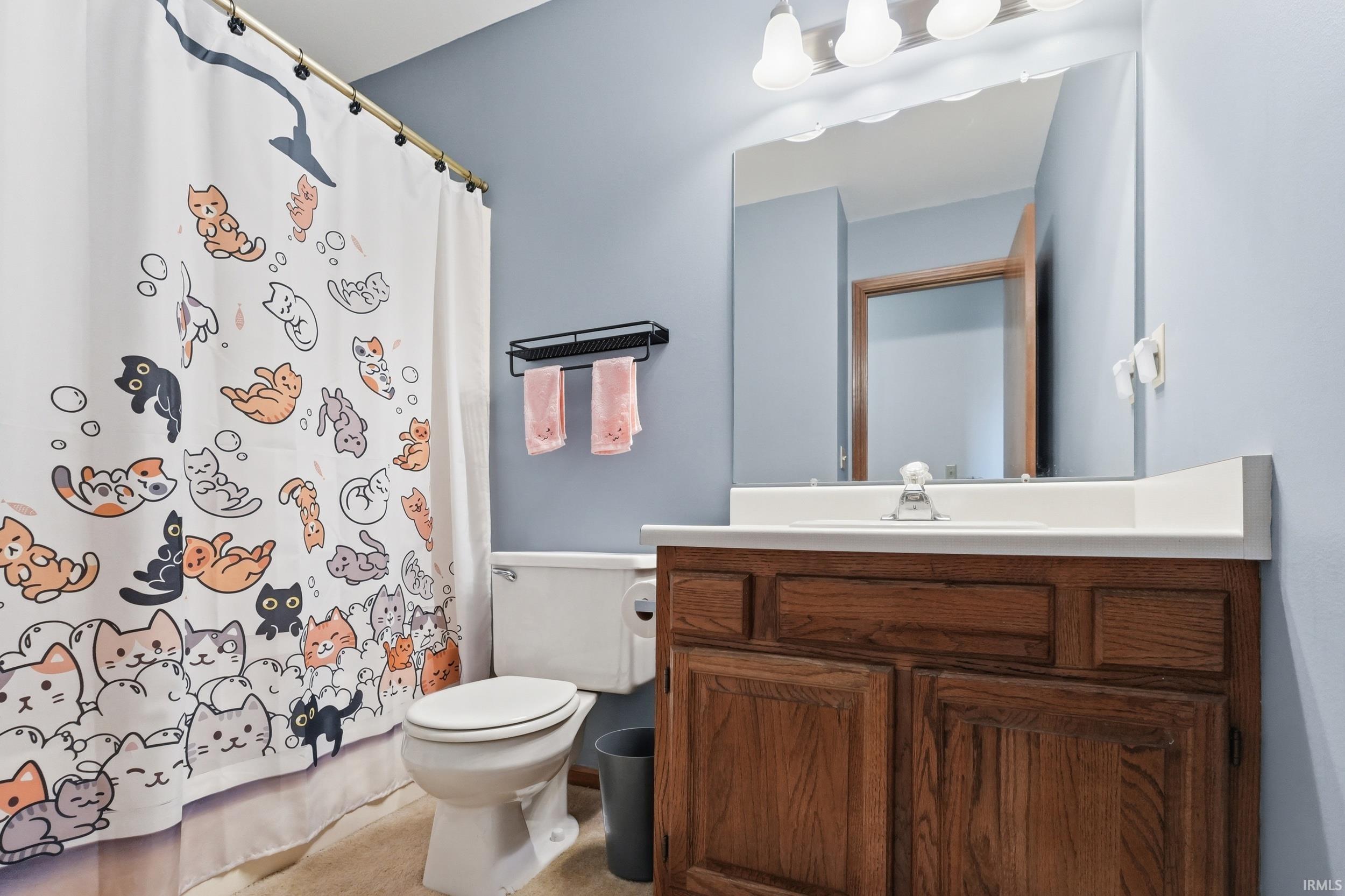 Bathroom featuring a wood-finish vanity with an integrated sink and countertop, a wall-mounted mirror, and a three-light fixture