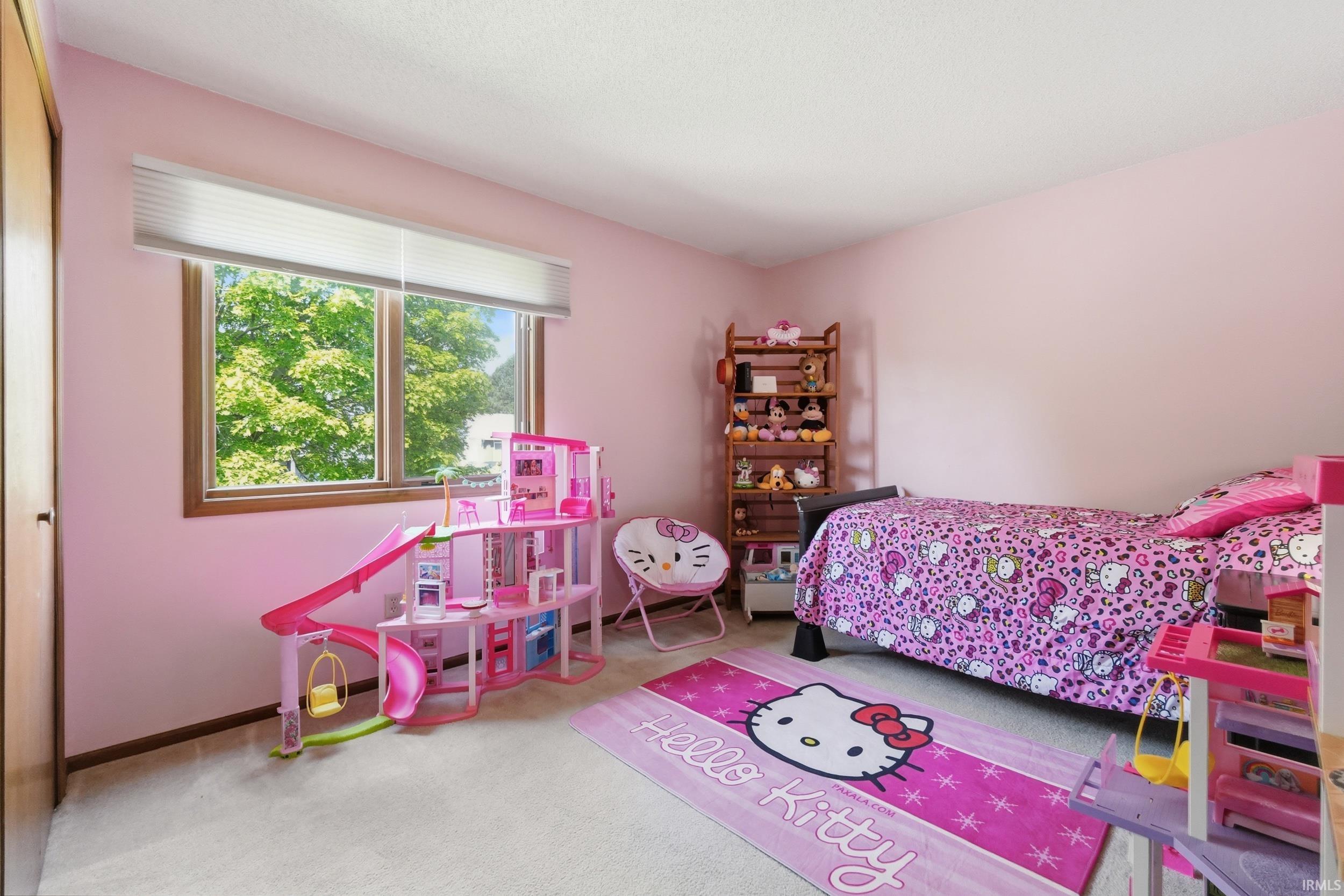 Carpeted room featuring a large window with white blinds, wood trim, and light pink walls