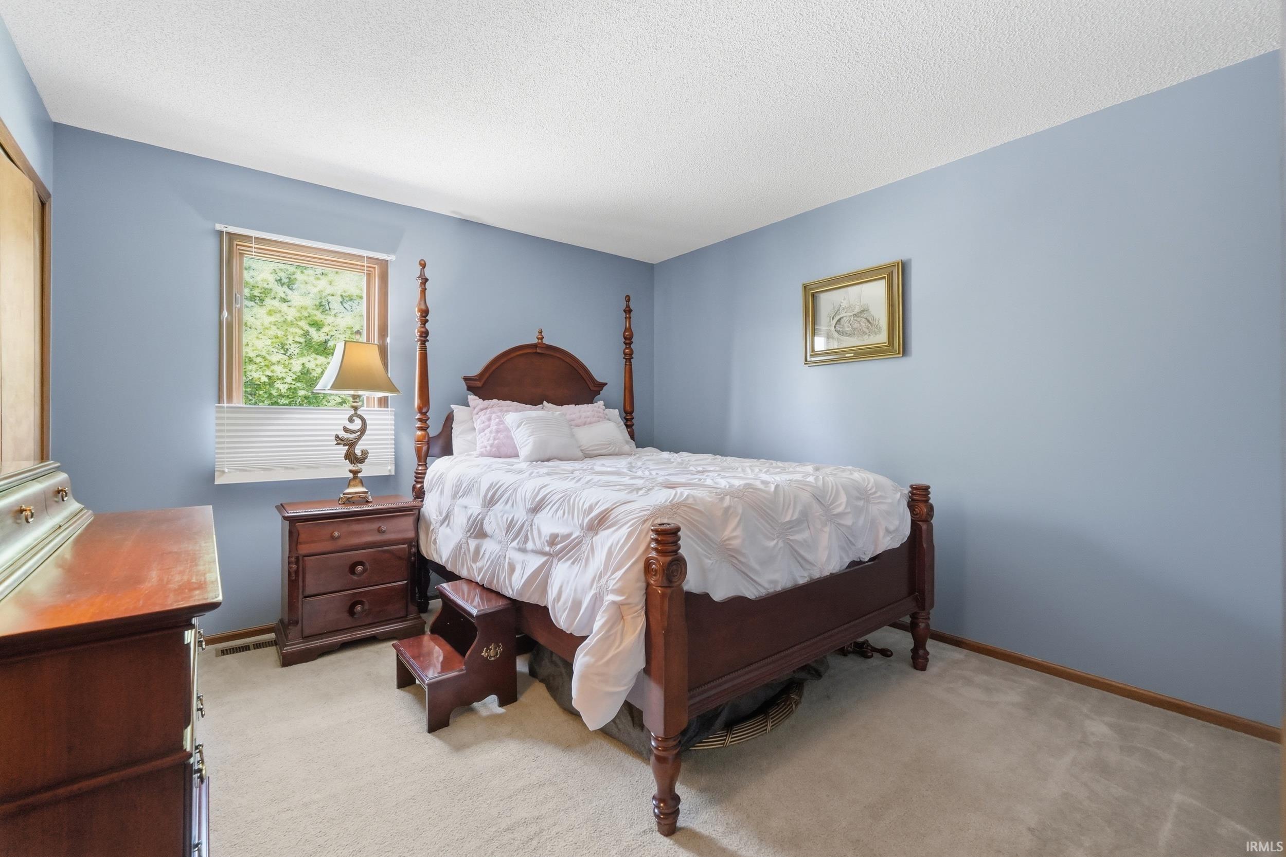 Spacious room featuring light blue walls and a neutral carpeted floor
