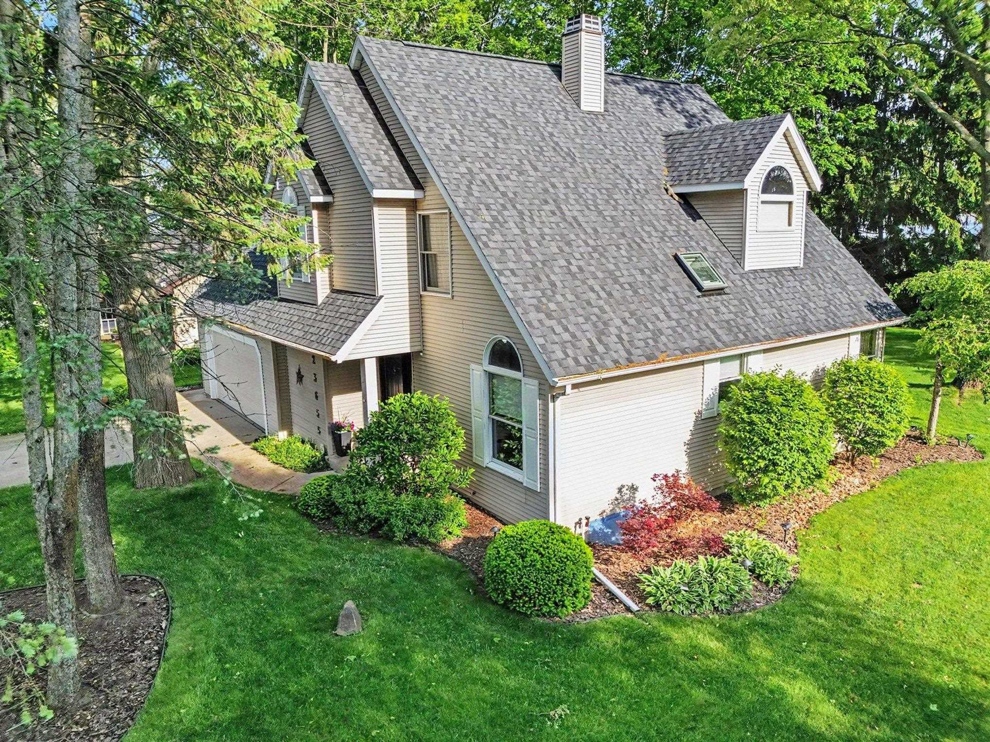 Two-story residence featuring light-toned siding and a multi-pitched shingled roof