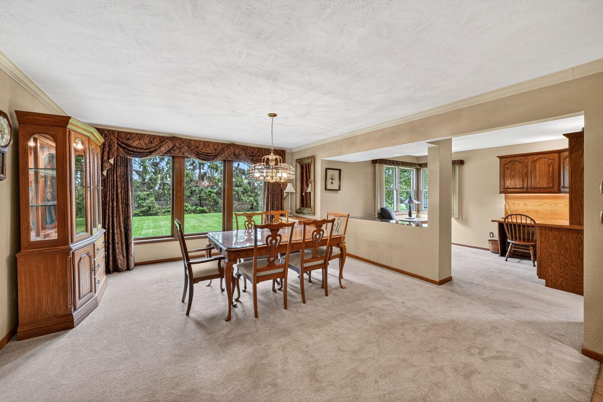 Dining area featuring a crystal chandelier and expansive window overlooking a green lawn