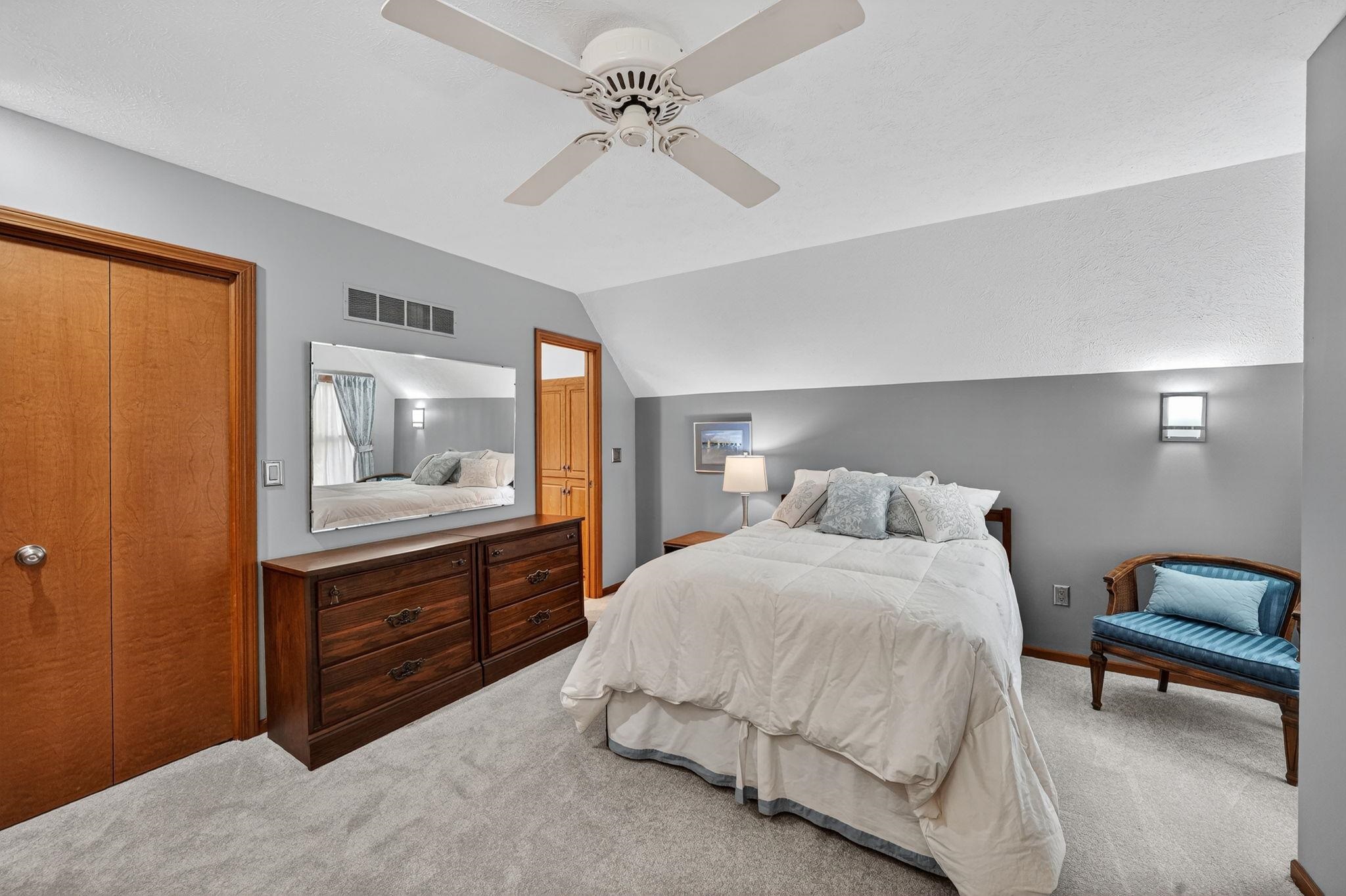 Carpeted room featuring a ceiling fan, wall-mounted lighting, and built-in wood doors