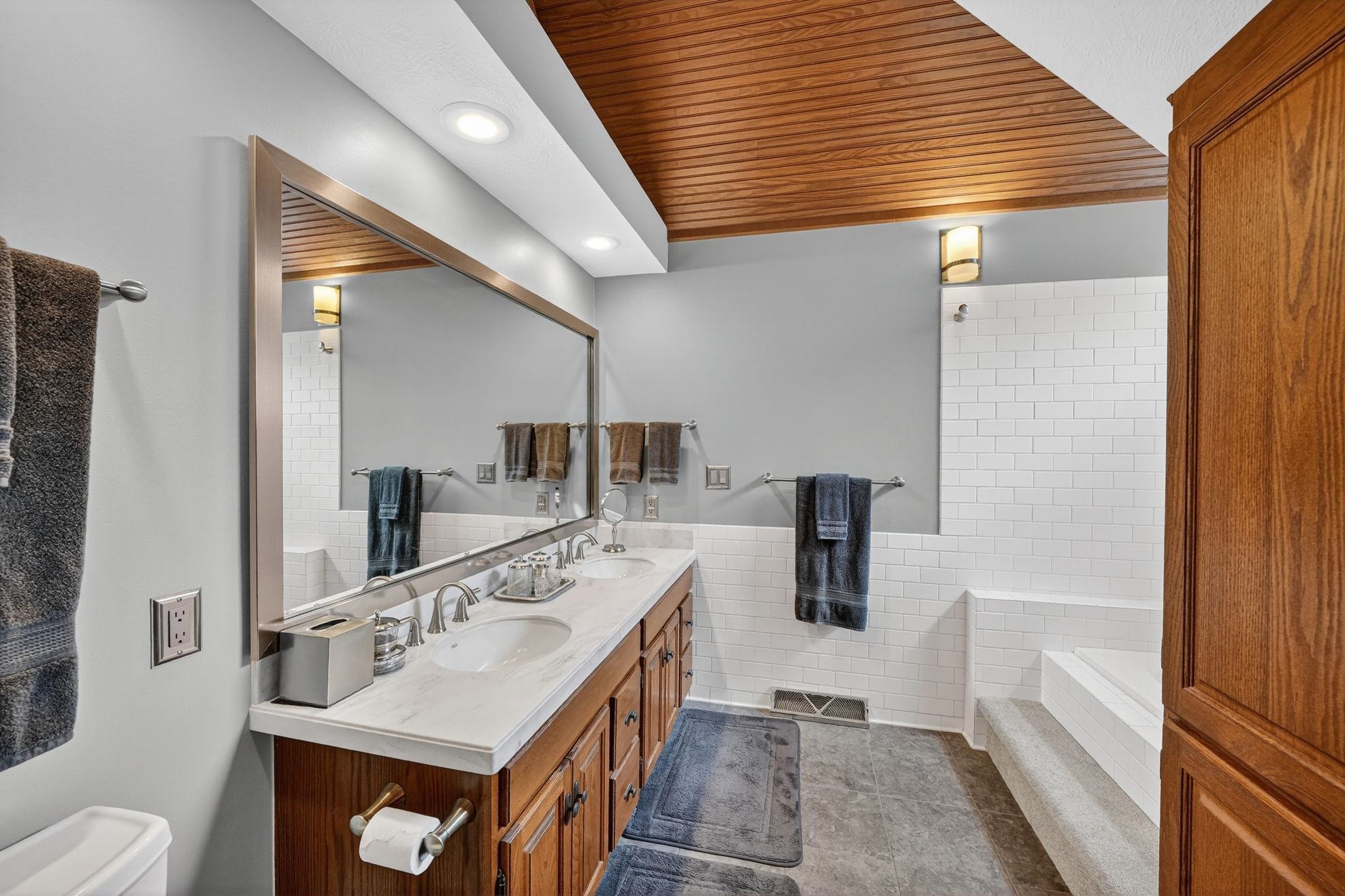 Double vanity with integrated sinks and brushed nickel fixtures, set against a full-length framed mirror