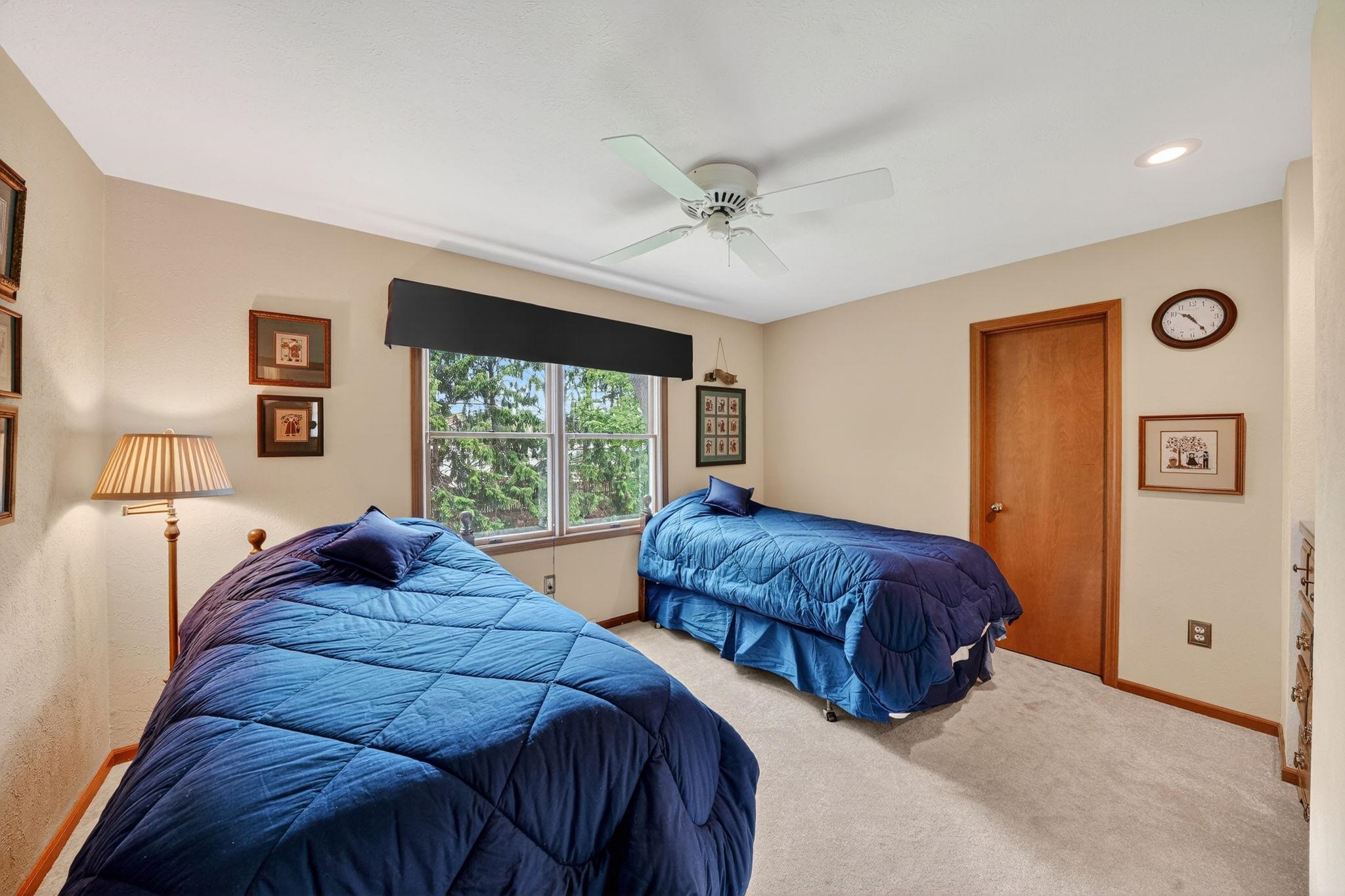 Bedroom featuring neutral-toned walls, light-colored carpet, and a ceiling fan with integrated lighting
