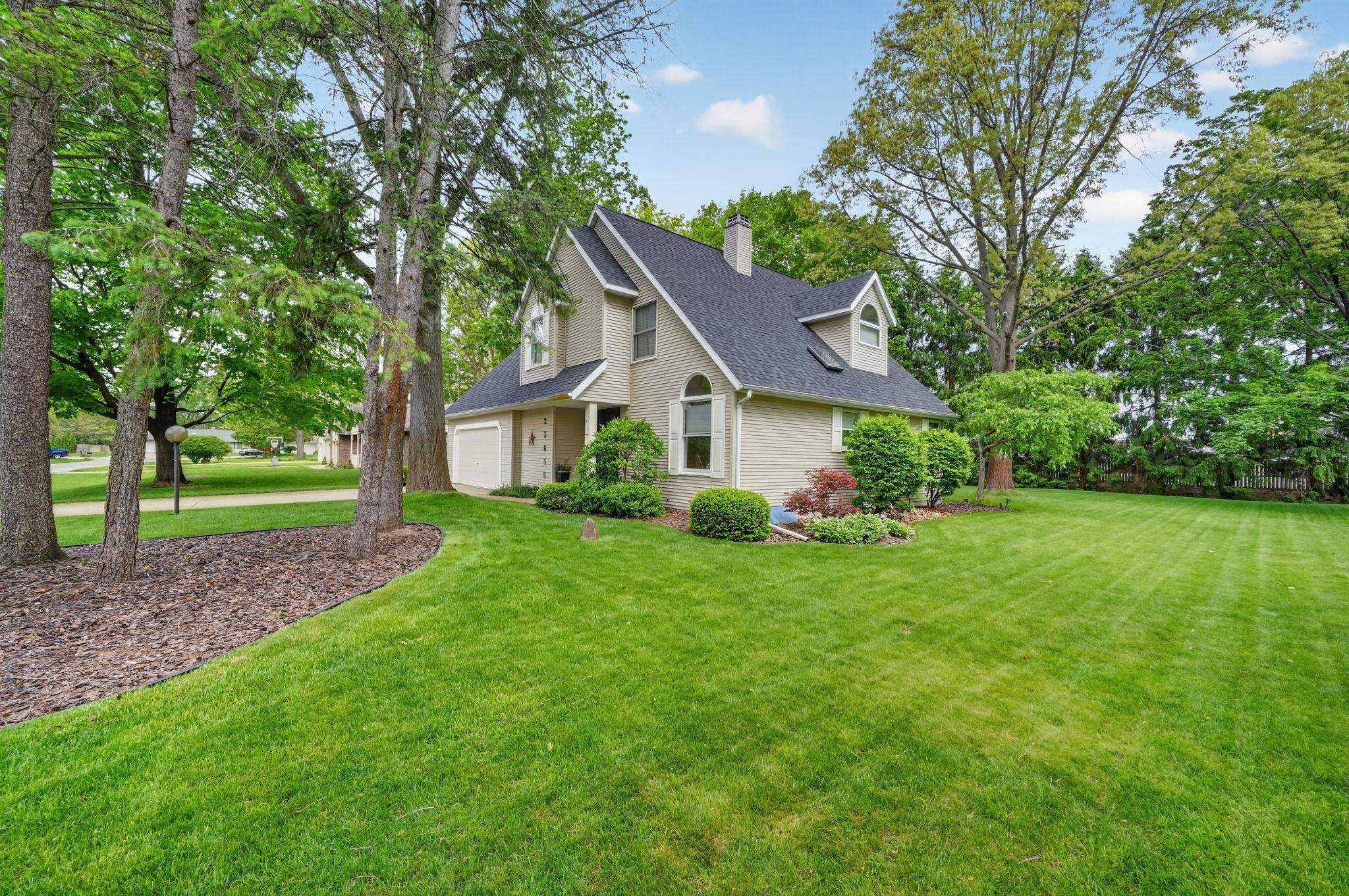 Two-story residence featuring a dark shingle roof, light-toned siding, and architectural dormer window