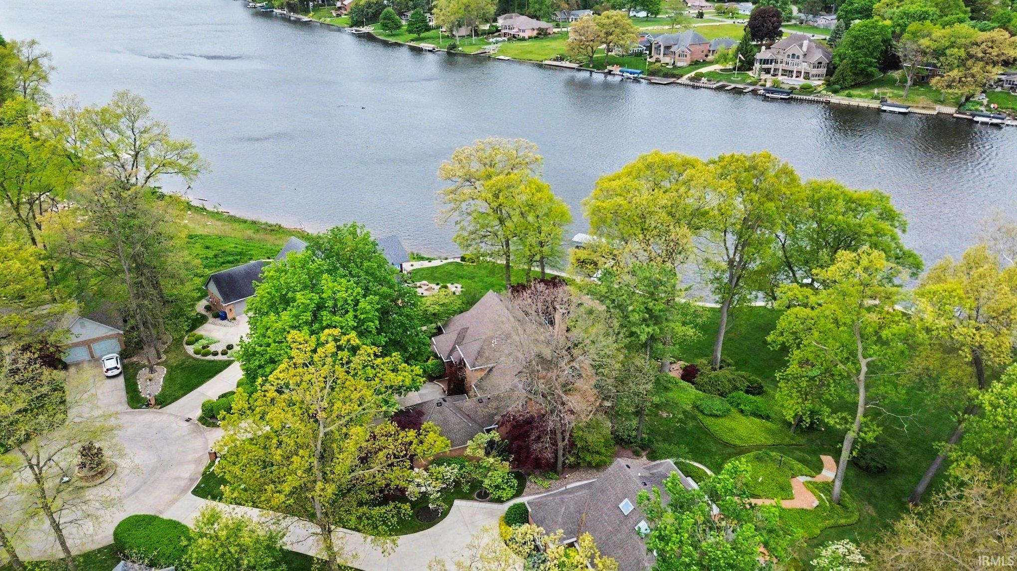 Waterfront property featuring a sloped, landscaped lot with mature trees