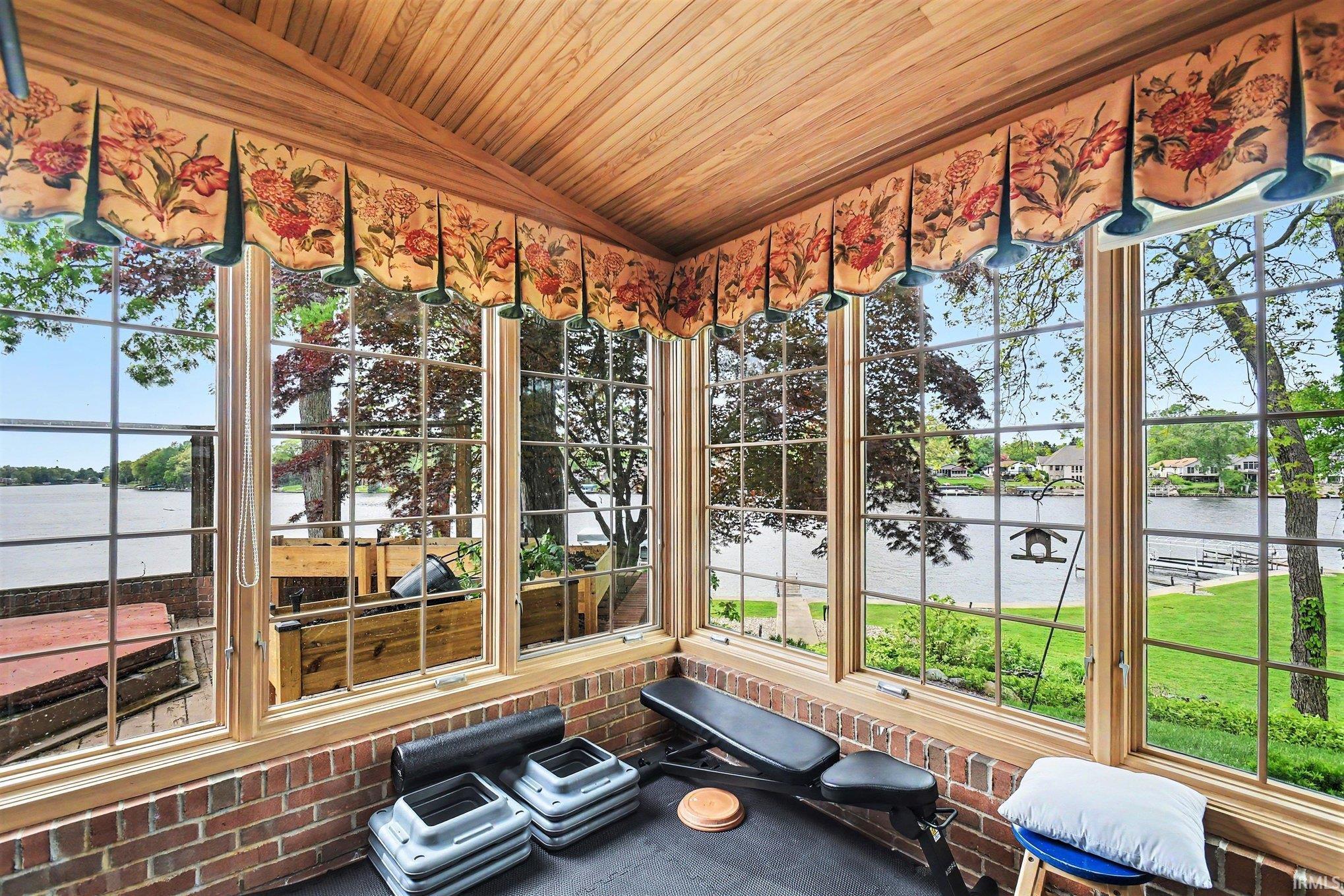 Sunroom featuring a wood-panel ceiling, brick half-walls, and expansive windows