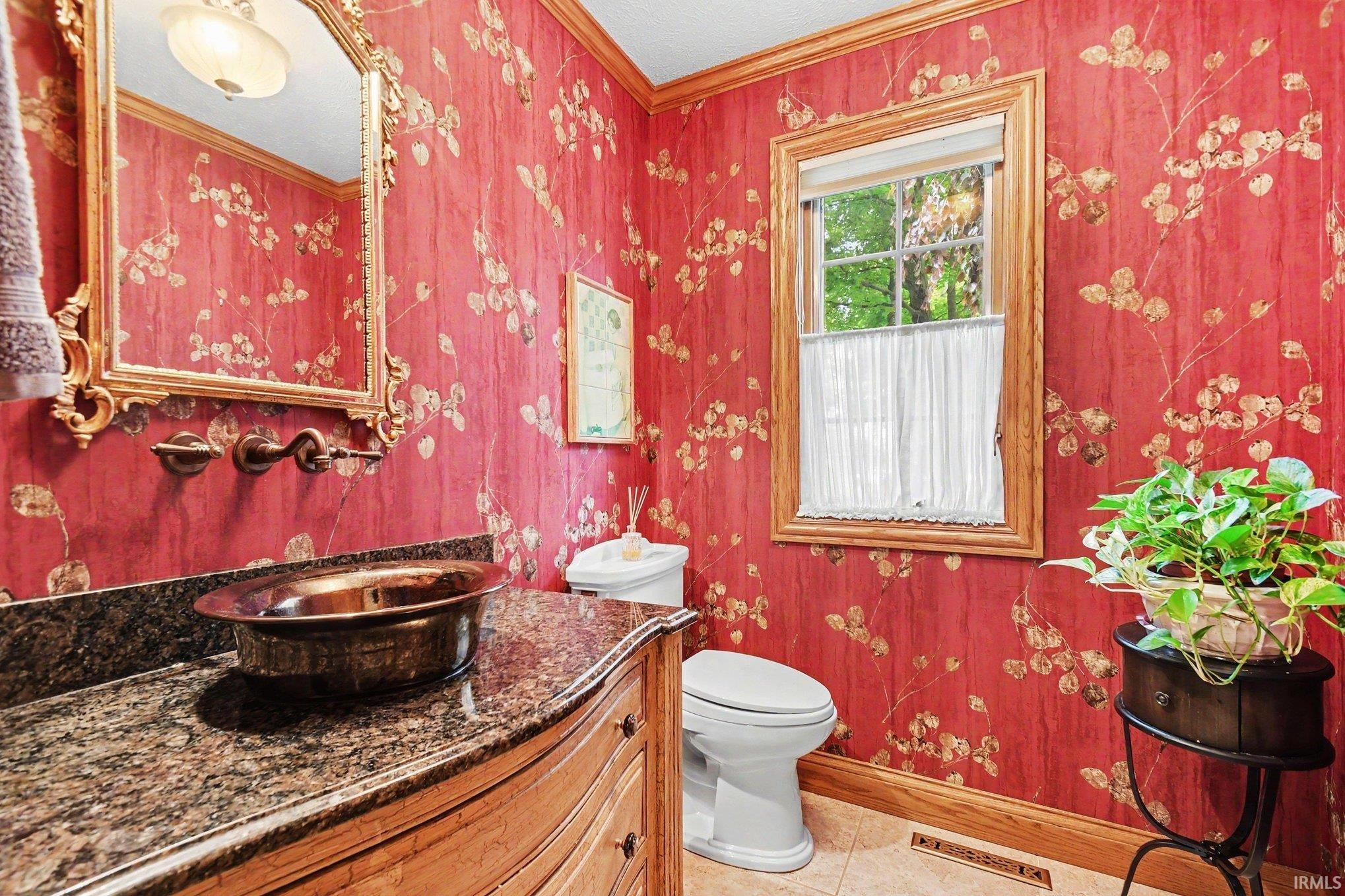 Vanity featuring a copper vessel sink, granite countertop, wall-mounted faucet, and an ornate framed mirror