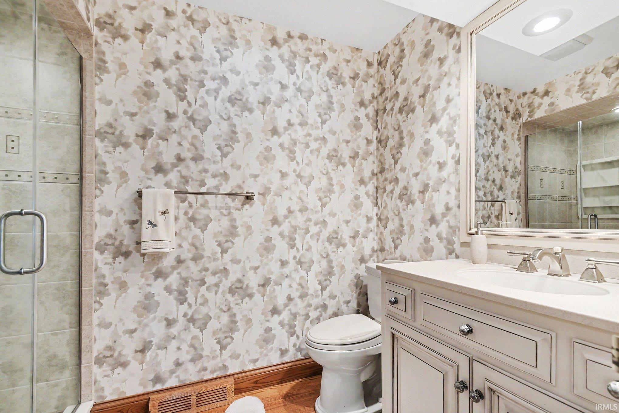 Bathroom featuring a single vanity with a light-toned countertop, a framed mirror, and chrome fixtures
