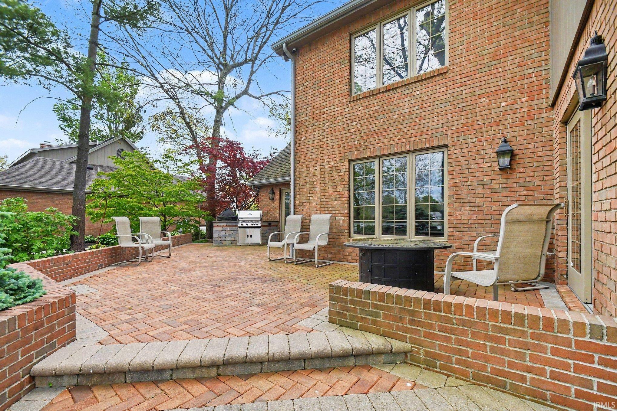 Expansive brick paver patio featuring tiered brick planters and a built-in outdoor cooking area