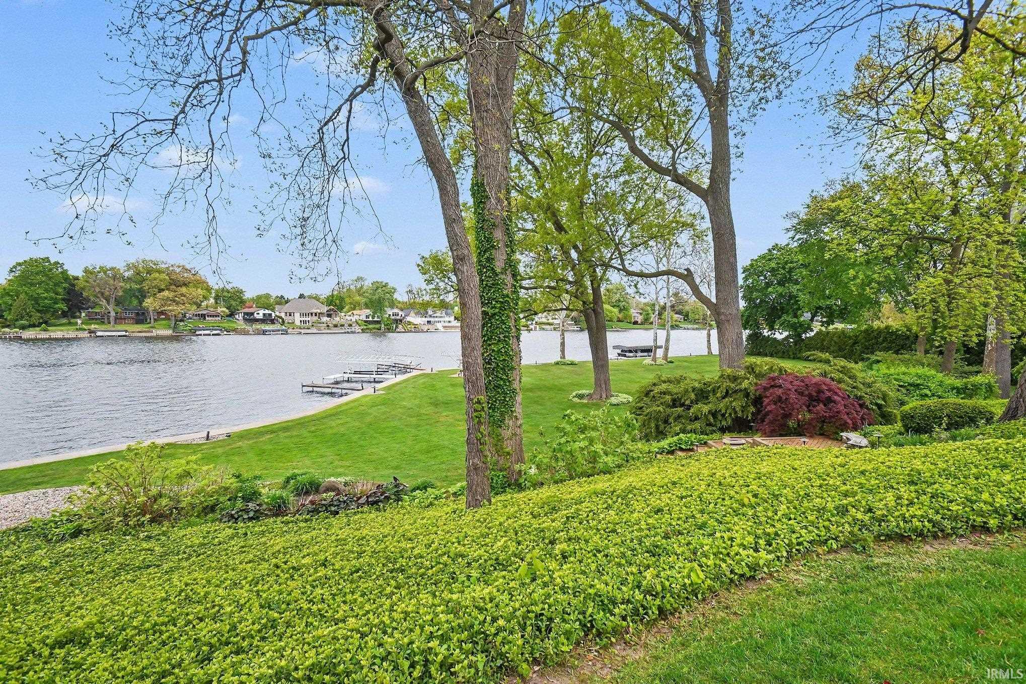 Expansive waterside property featuring mature trees, manicured lawns, and varied landscaping