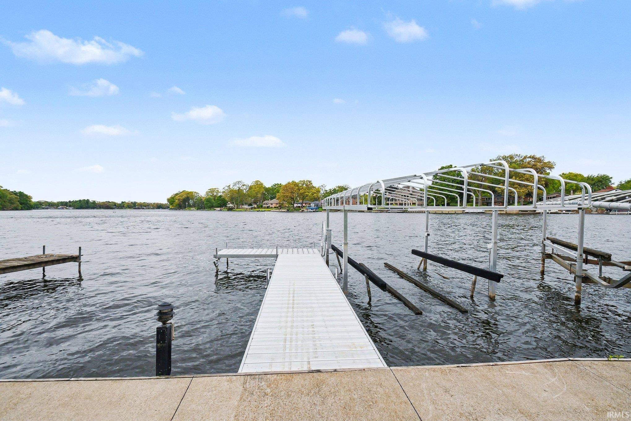 Waterfront property featuring a concrete dock, extended pier, and metal boat lift structure