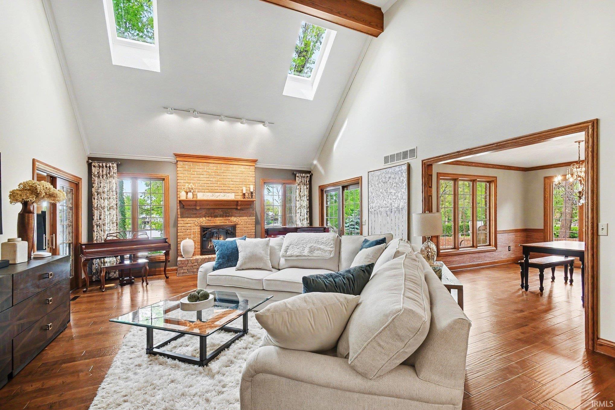 Living area featuring a vaulted ceiling with exposed wood beams and multiple skylights