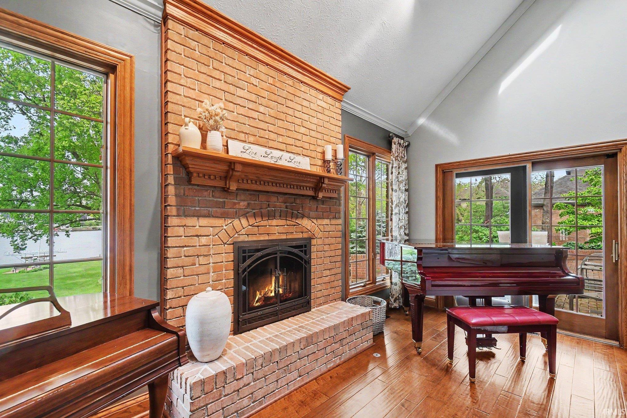 Brick fireplace with an arched firebox and an extended brick hearth, flanked by large windows with wood trim