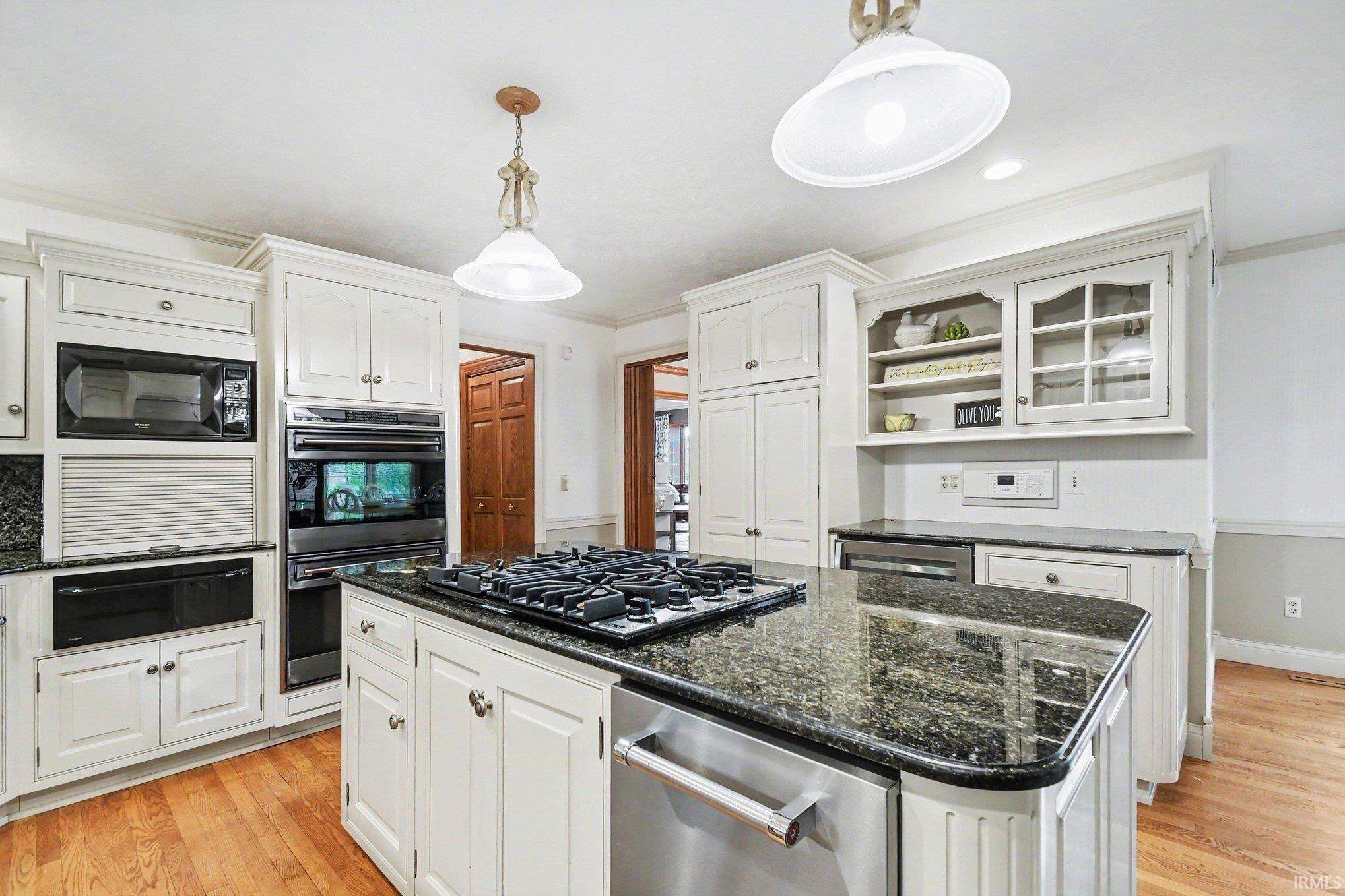 Kitchen featuring a central island with a gas cooktop, granite countertops, and white cabinetry