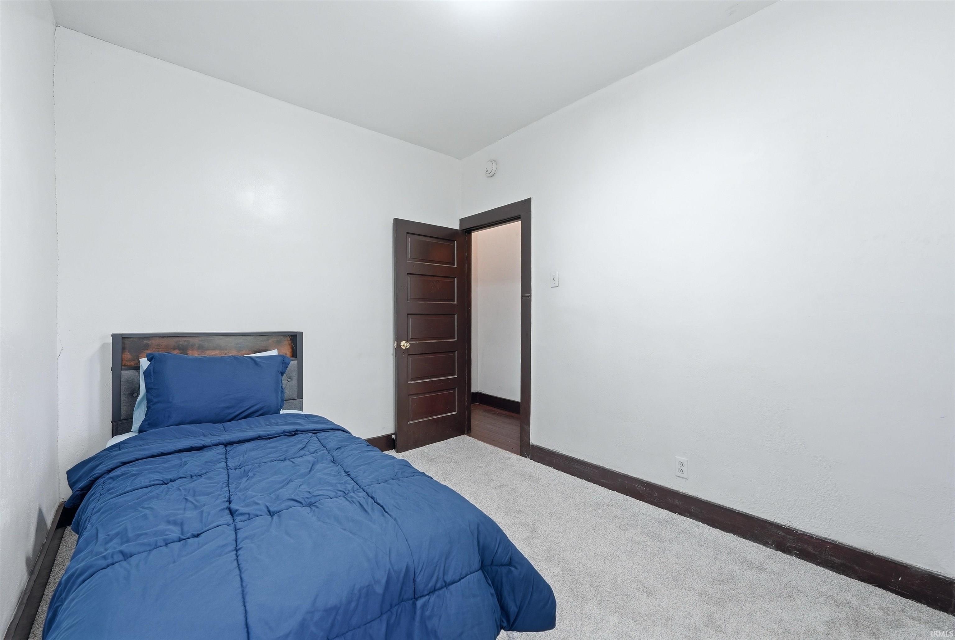 Bedroom featuring light gray carpet, white painted walls, and dark wood trim