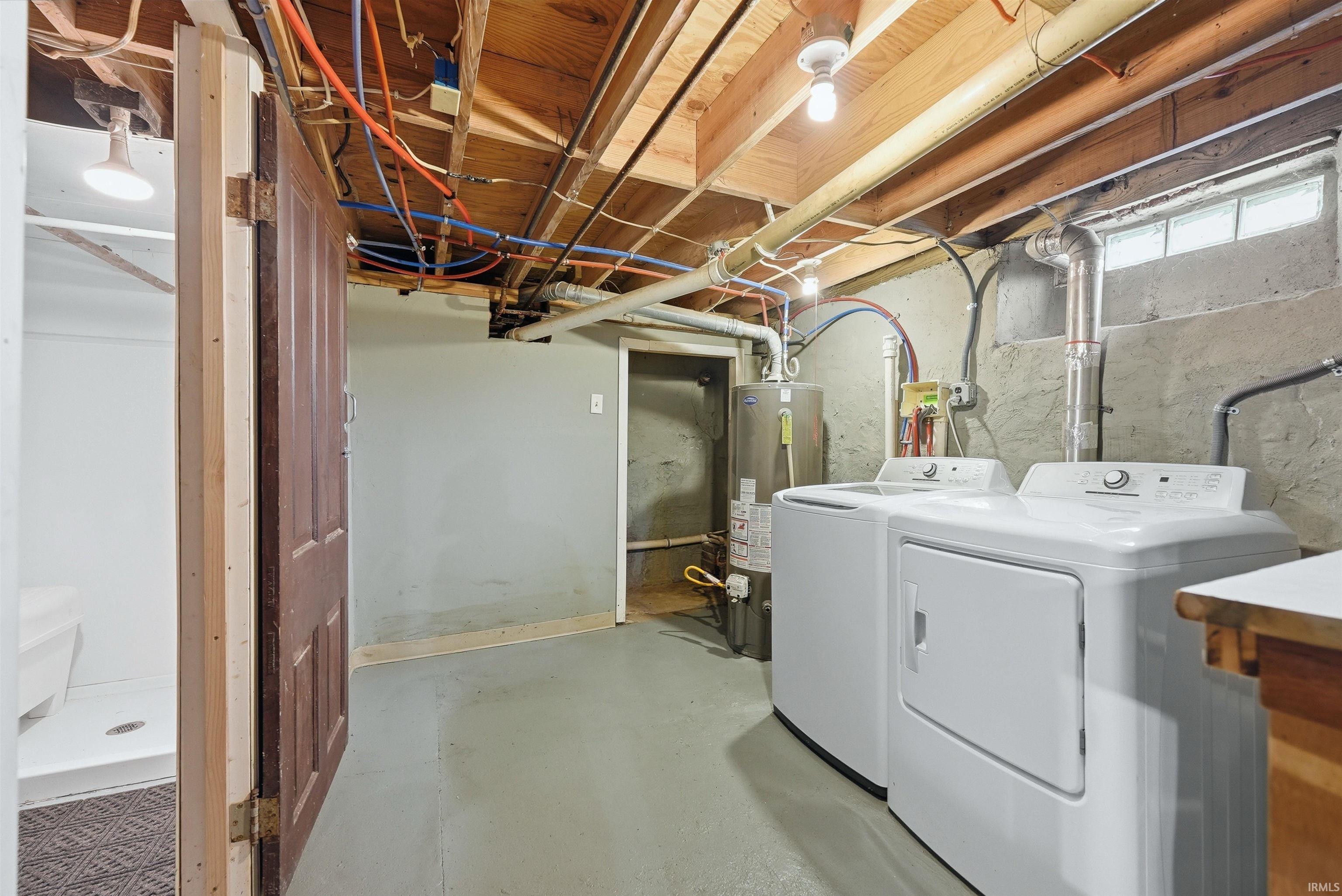 Laundry area featuring a utility sink, a washer and dryer, exposed ceiling joists, and a glass block window