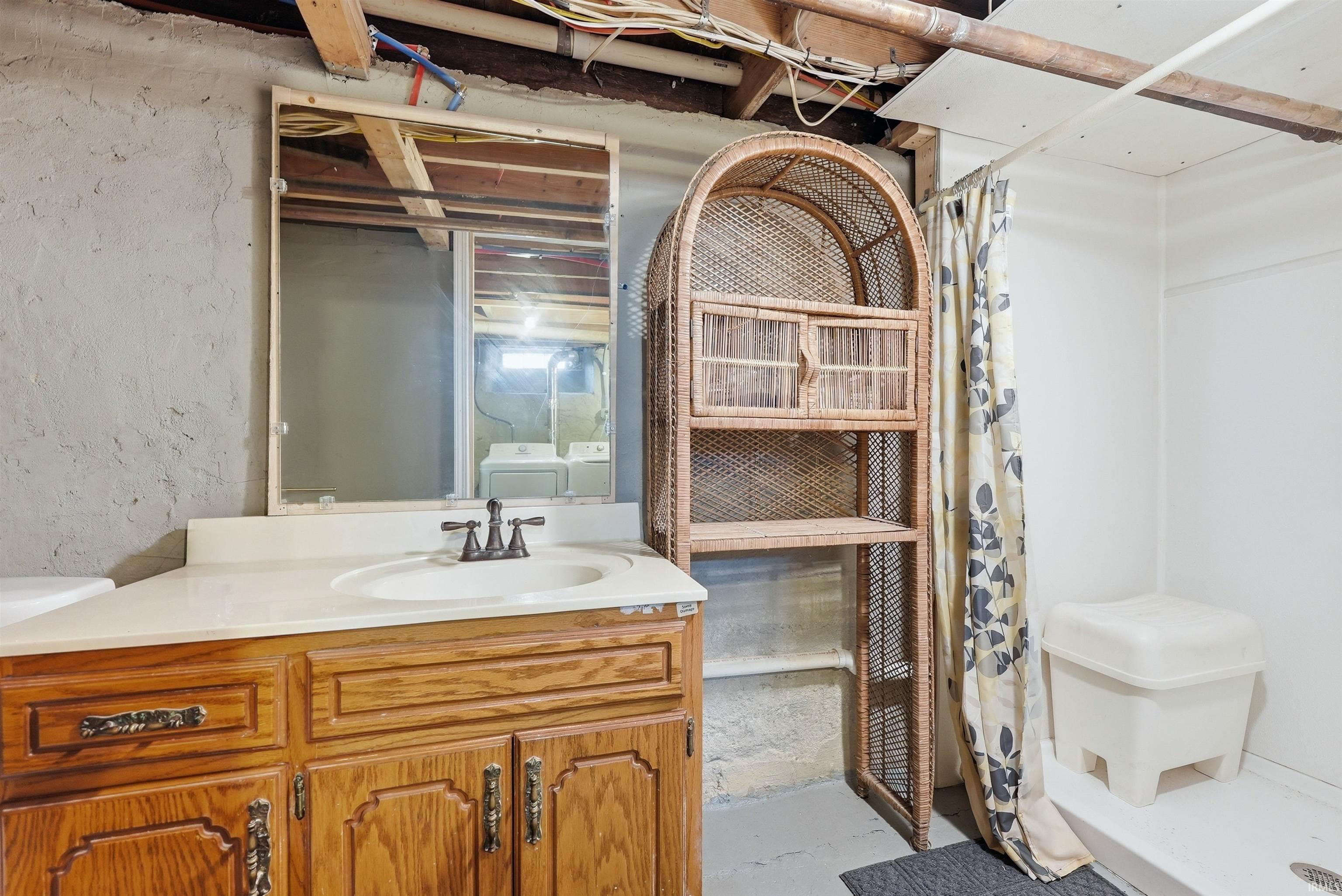 Bathroom vanity with a built-in sink, wall-mounted mirror, and a shower stall with a white base