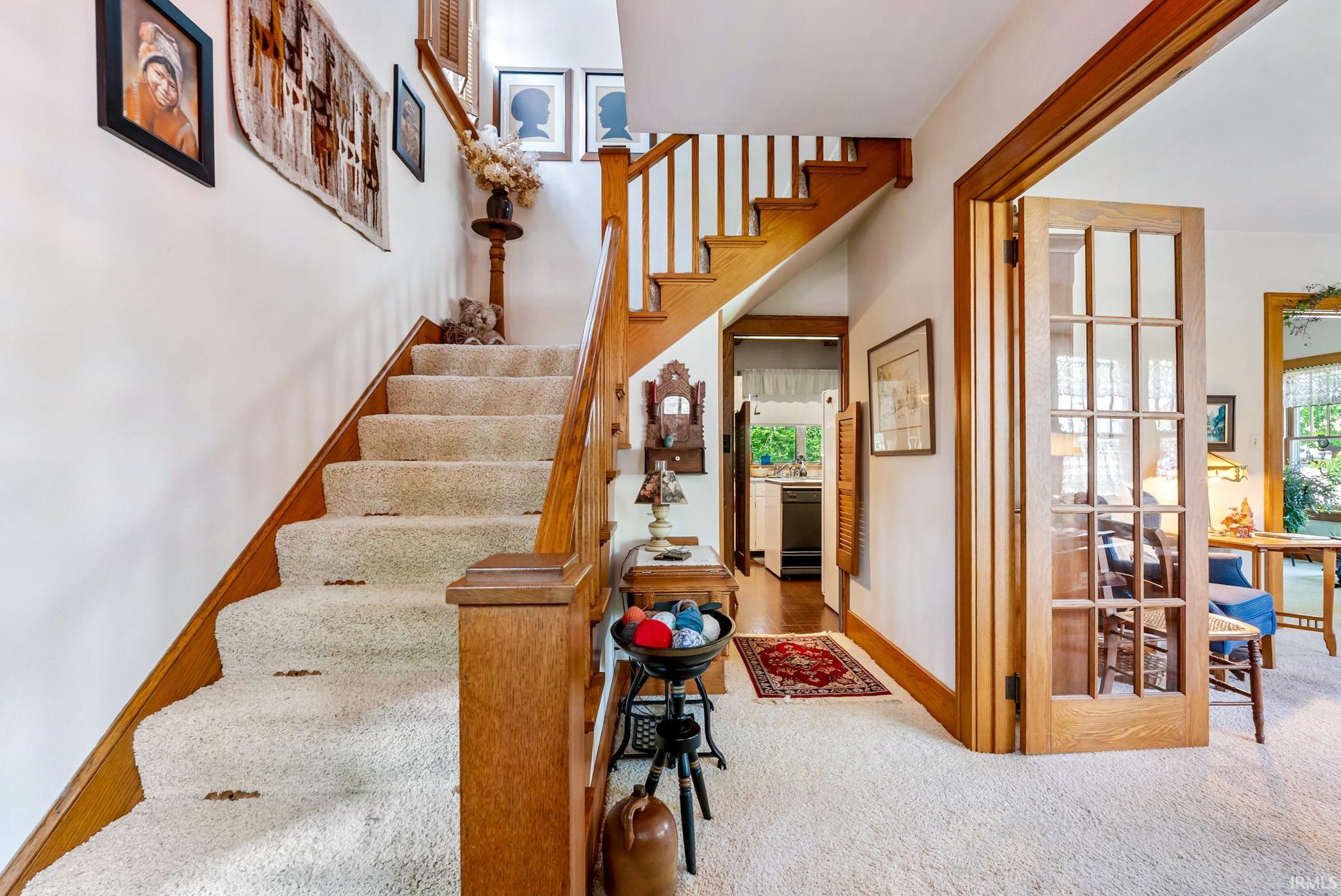 Wood staircase with a carpet runner, leading to an upper level