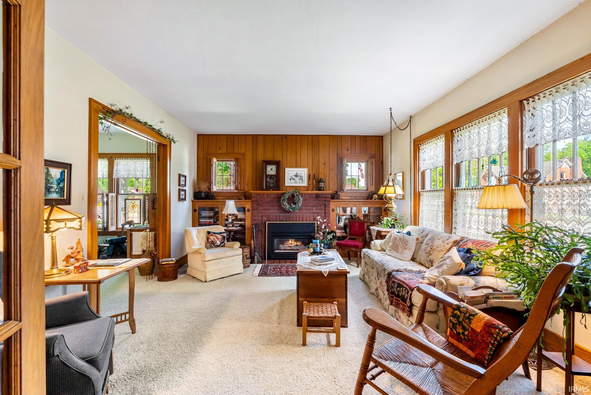 Living space featuring a brick-surround fireplace, wood paneling, and built-in shelving