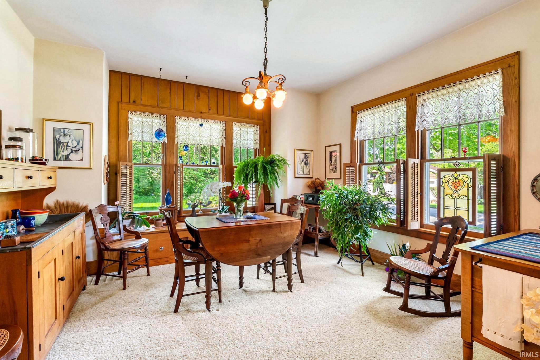 Light-filled room featuring extensive wood paneling, multiple windows with decorative stained glass accents, a built-in window seat, and built-in cabinetry with a dark countertop