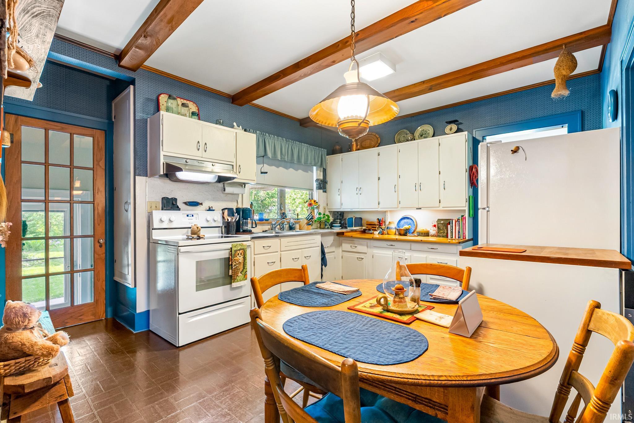 Kitchen featuring exposed wood-finish ceiling beams and a central dining area