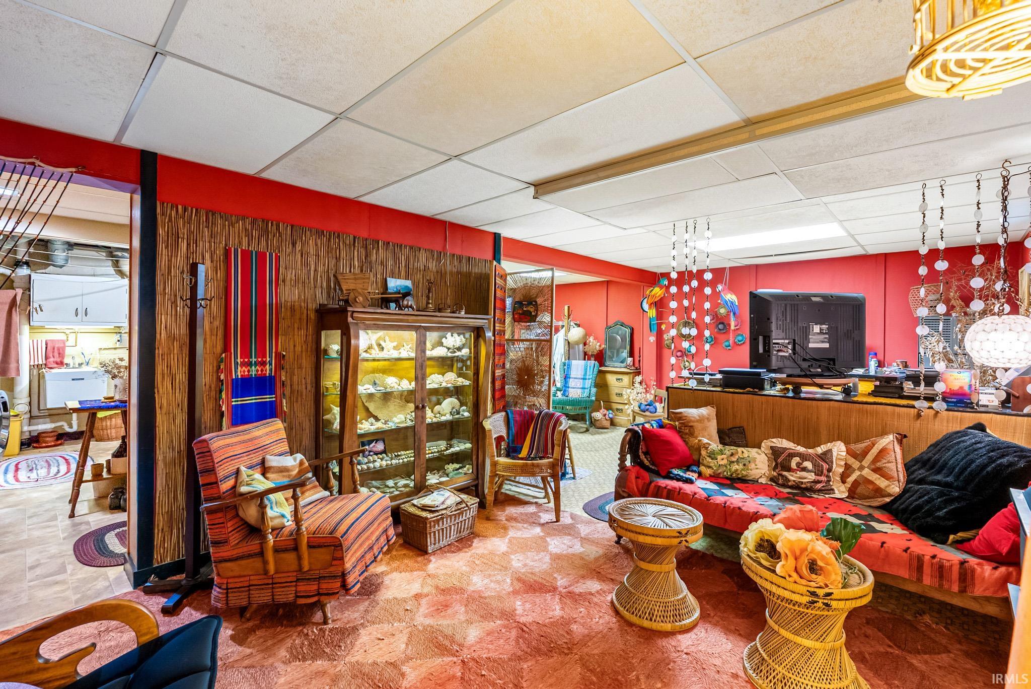 Recreation room featuring red accent walls, textured wood-paneling, and a drop ceiling