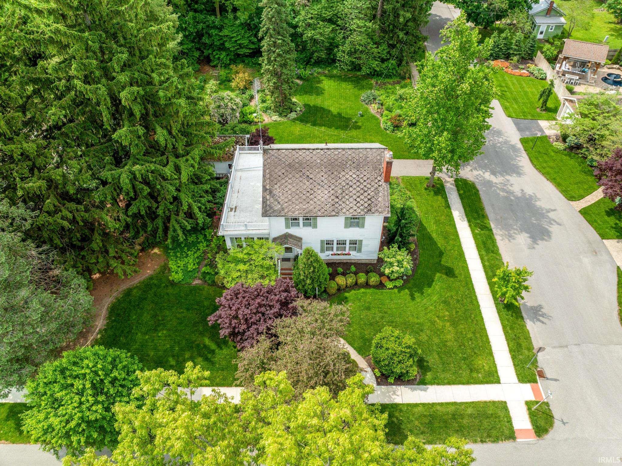 Aerial perspective showcasing a two-story residence with a gabled roof and a flat rooftop deck