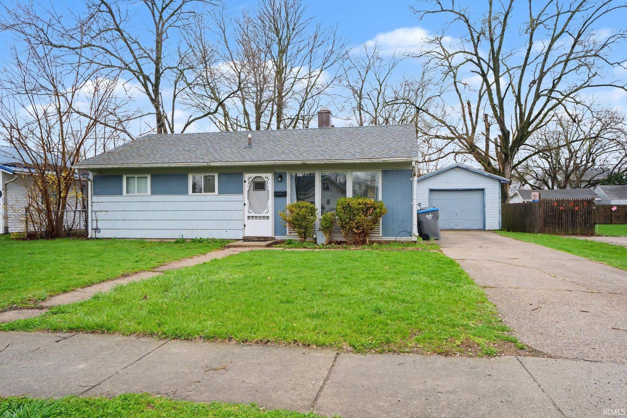 Ranch-style exterior with light blue siding, a dark gray shingle roof, and a prominent front door with a storm door