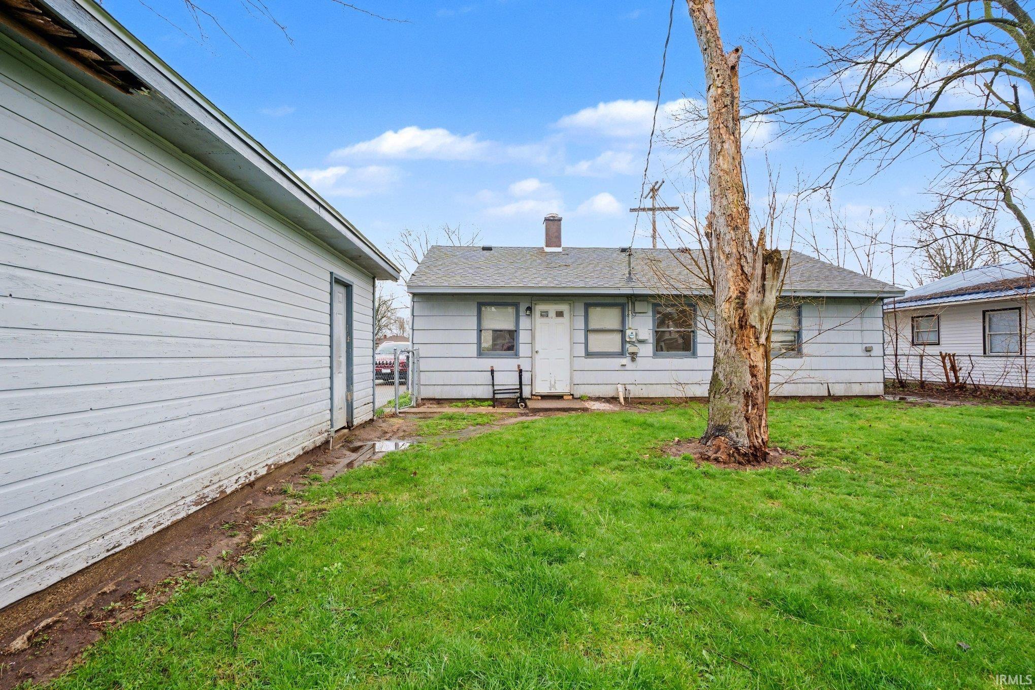 Rear exterior featuring a detached garage with vinyl siding and a fenced perimeter