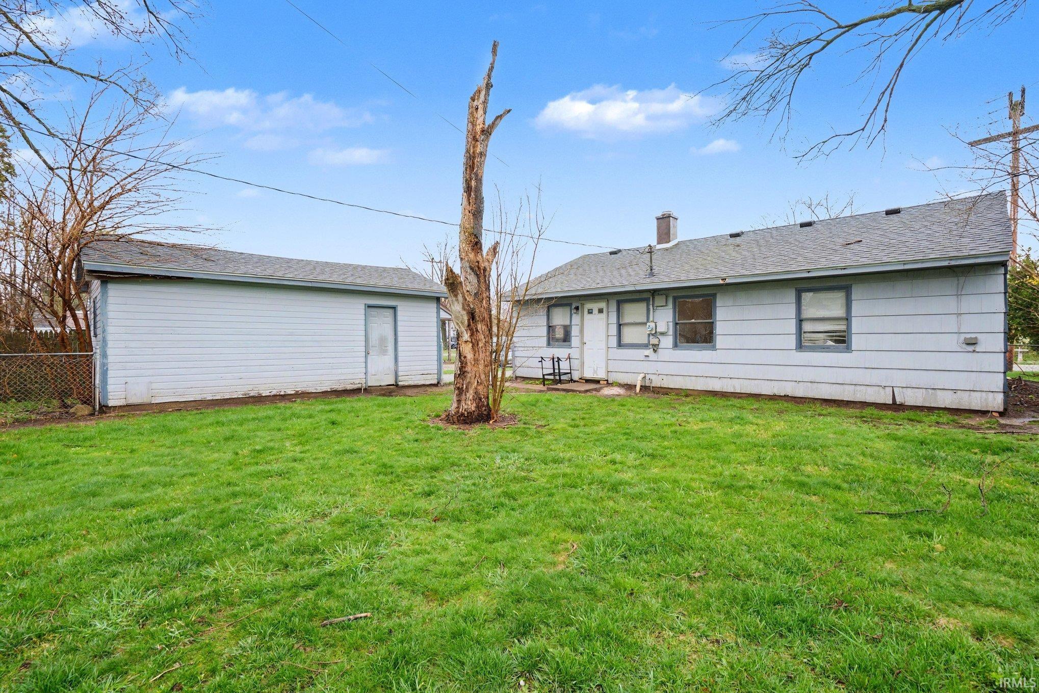 Expansive lawn area with a detached garage and a single-story residence