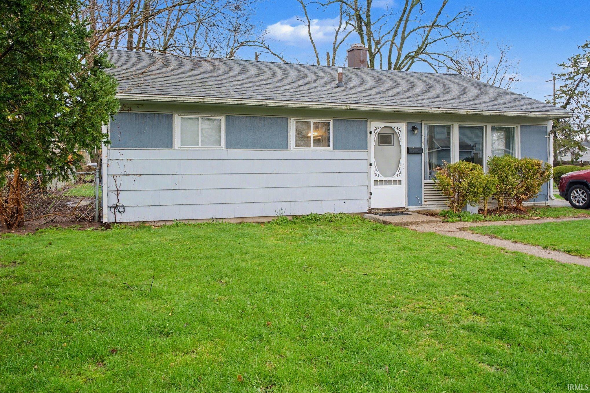 Single-story residence featuring light blue siding, a gray shingle roof, and a white storm door with decorative glass